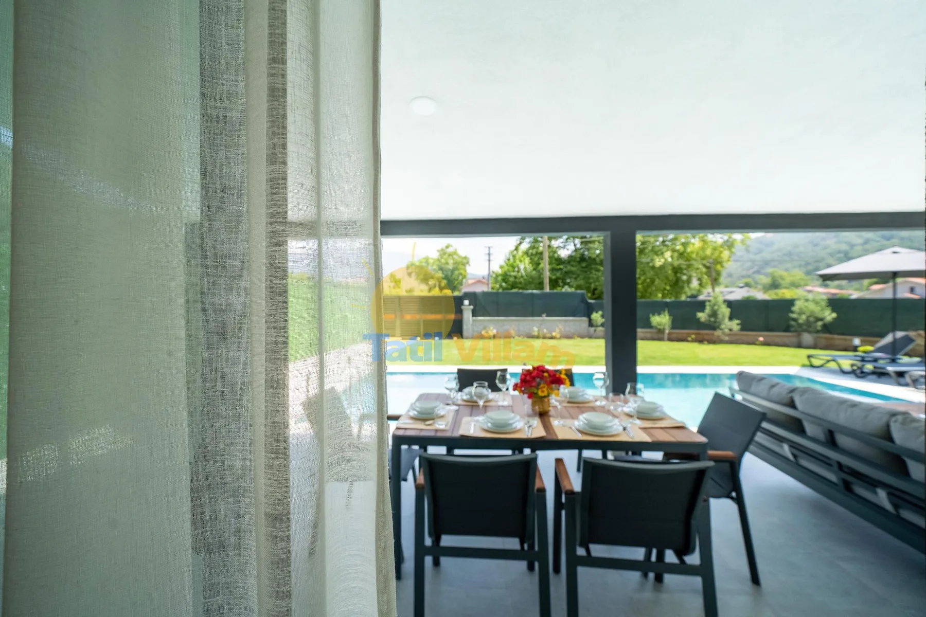 Un comedor da a una terraza con piscina y asientos al aire libre.