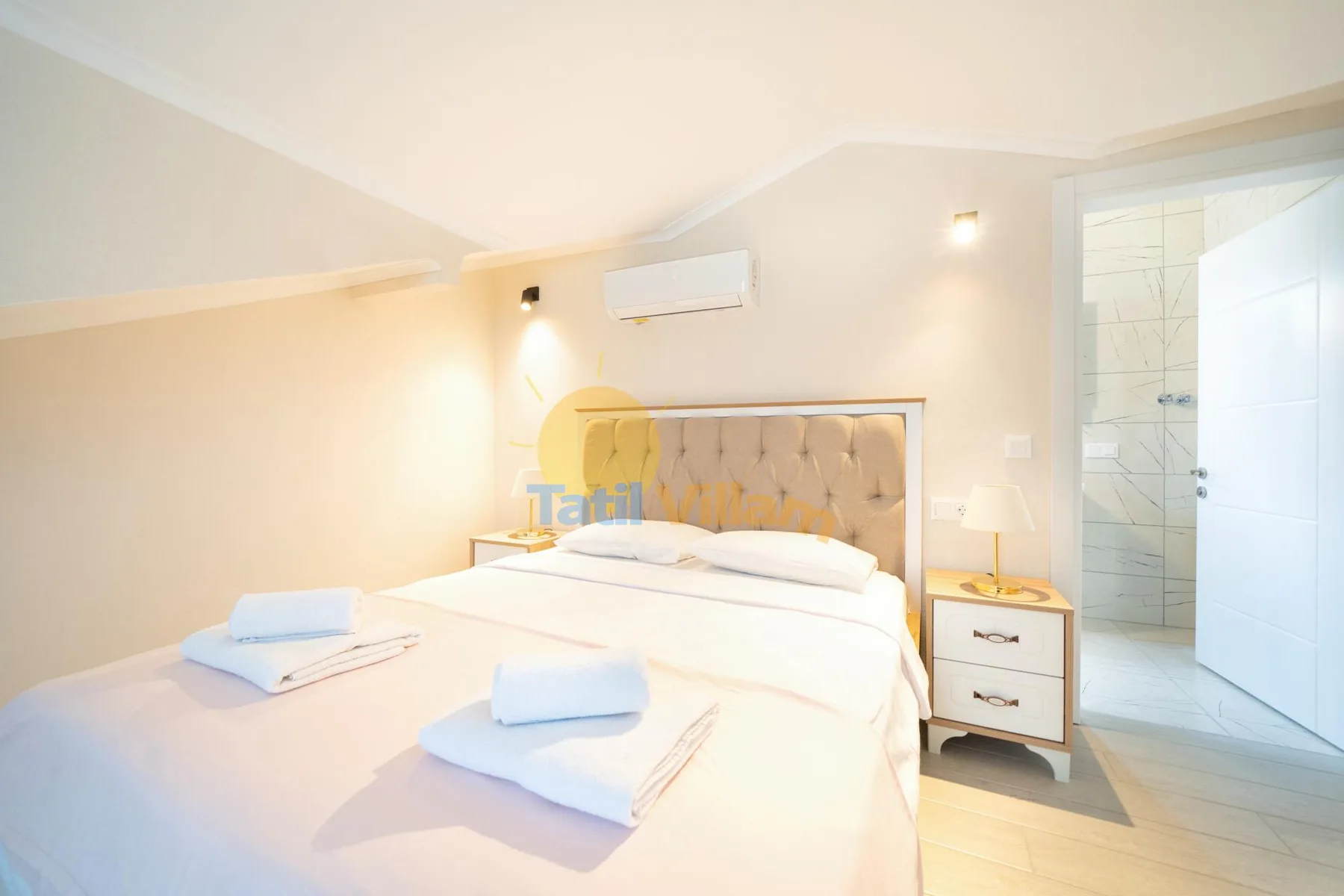 Un dormitorio luminoso con una cama grande y una puerta abierta al baño.