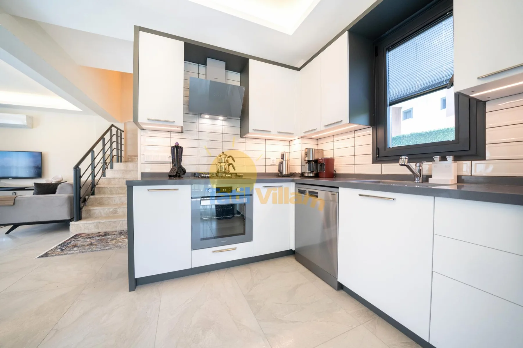 Una cocina moderna con gabinetes blancos, horno empotrado y una ventana.