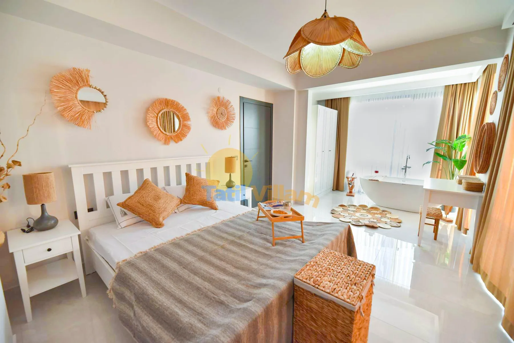 A bright bedroom has a white bed with gray bedding, woven wall decor, and an open doorway to a bathtub.