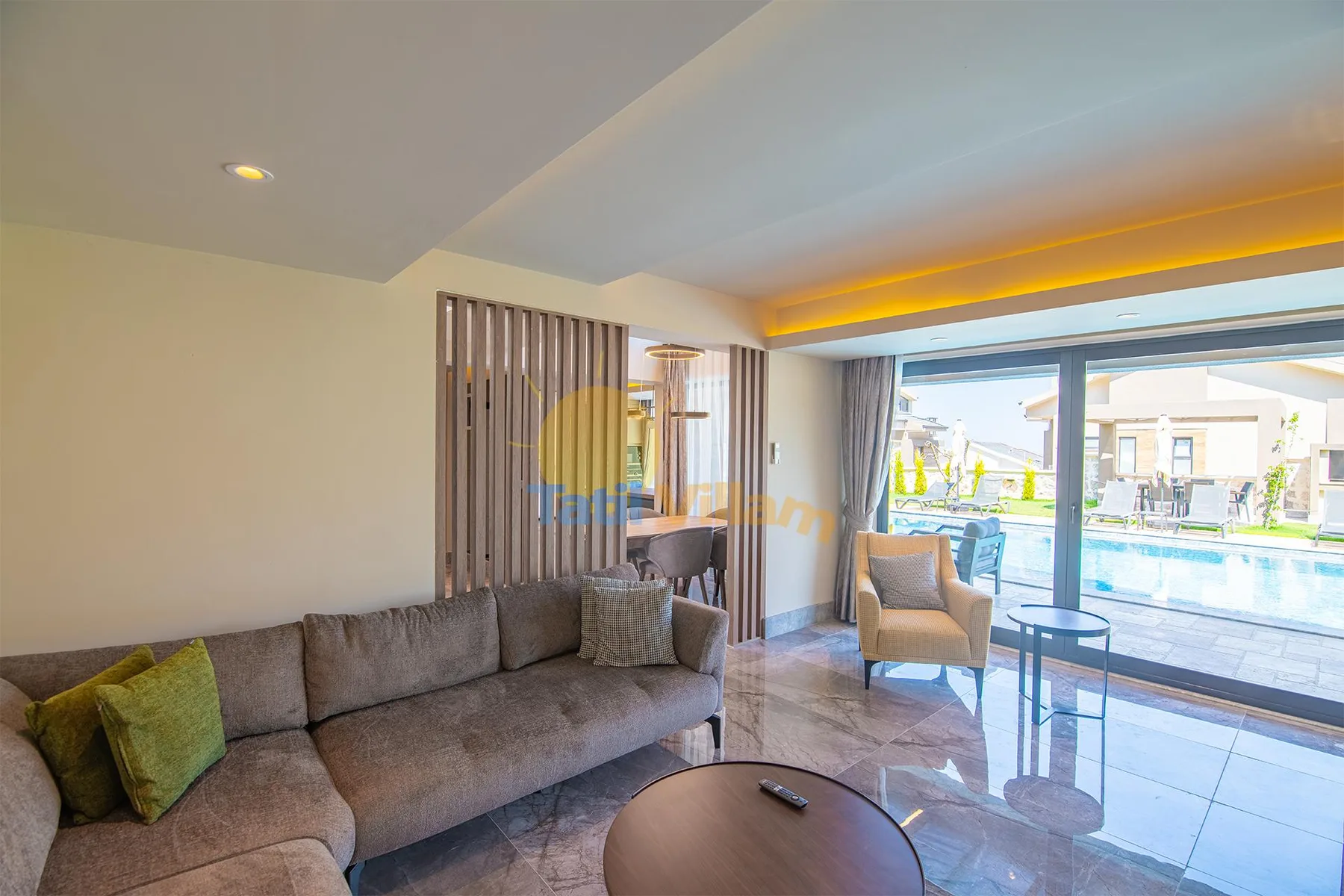 A modern living room has a gray sectional sofa, glass coffee table, and large sliding doors opening onto a patio.