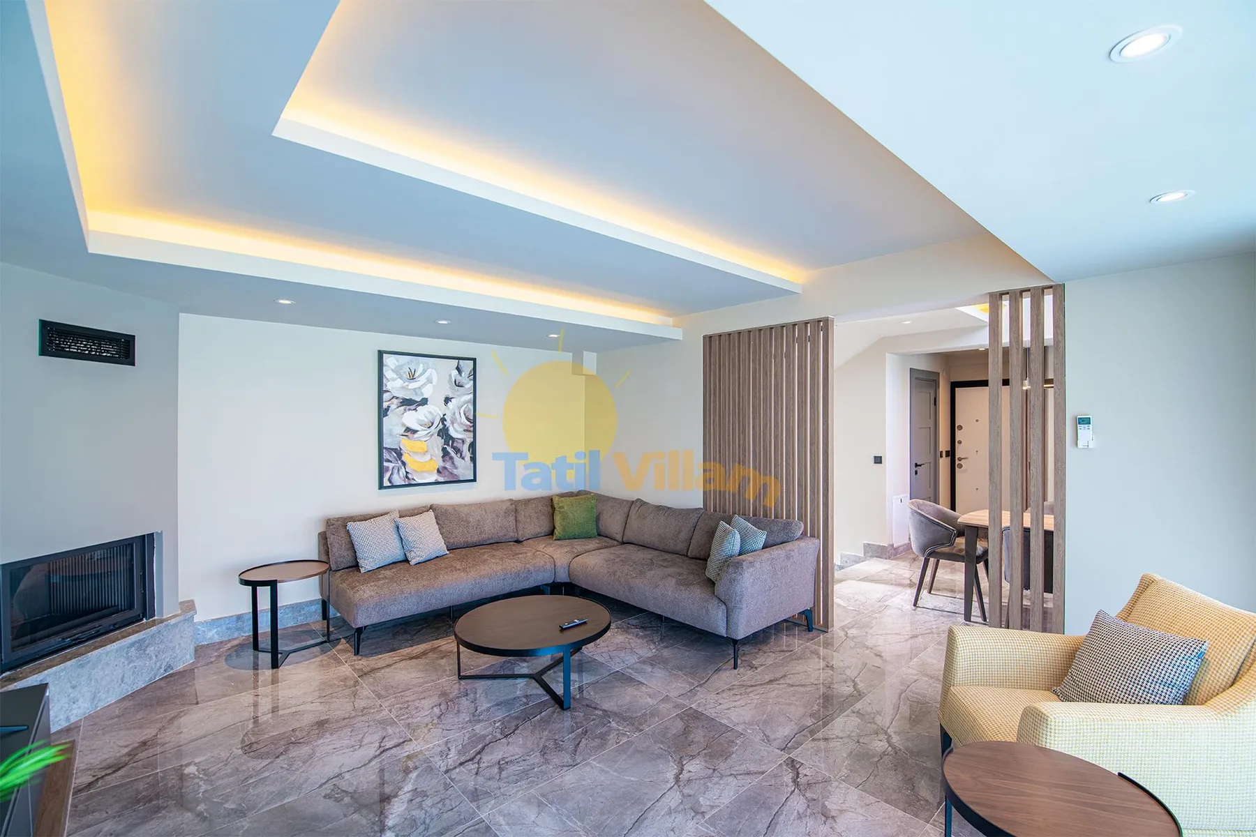 A modern living room with an L-shaped sofa, coffee table, armchairs, and a slatted divider.