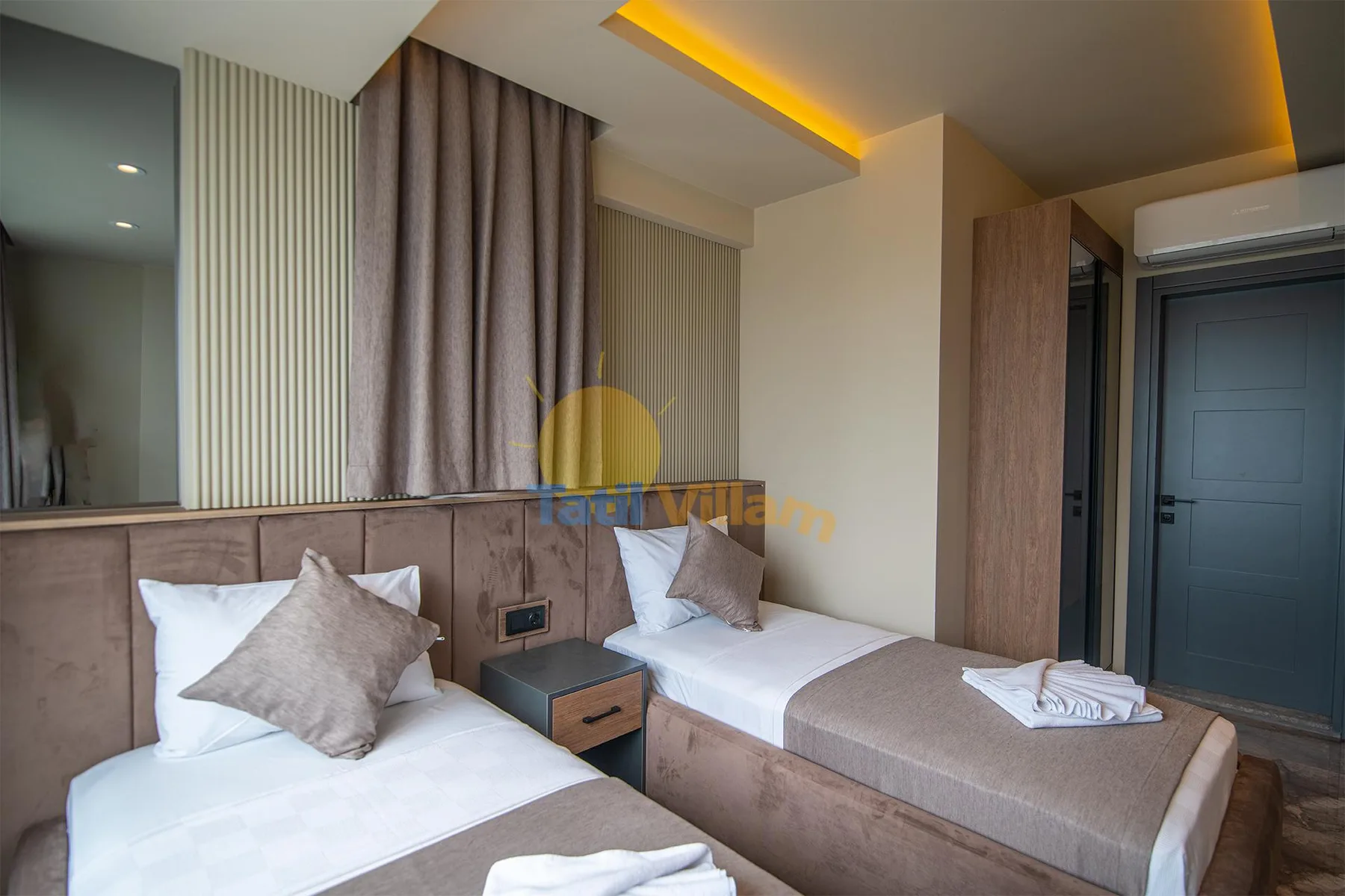 A modern twin bedroom has two single beds, upholstered headboards, and warm recessed ceiling lighting.