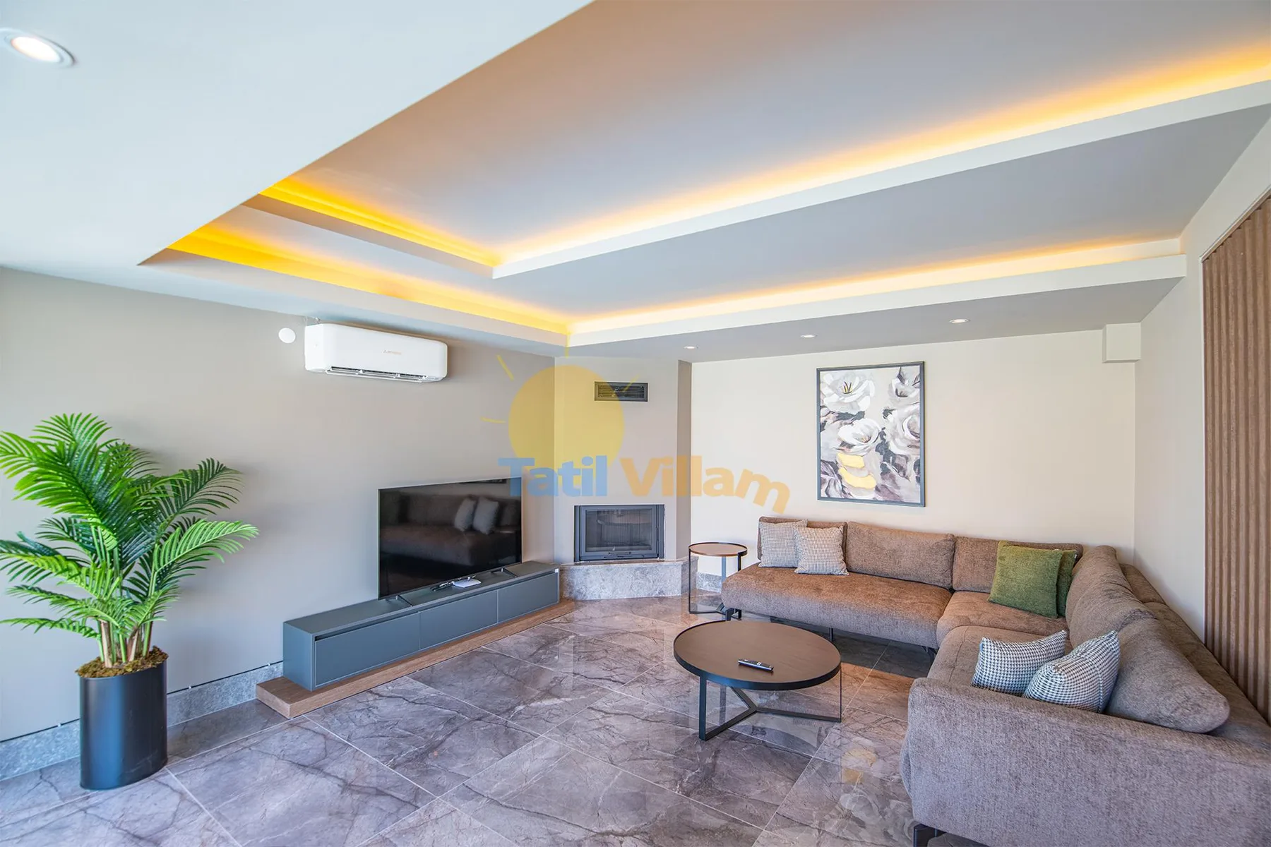 A modern living room with a sectional sofa, television, coffee table, and recessed ceiling lighting.