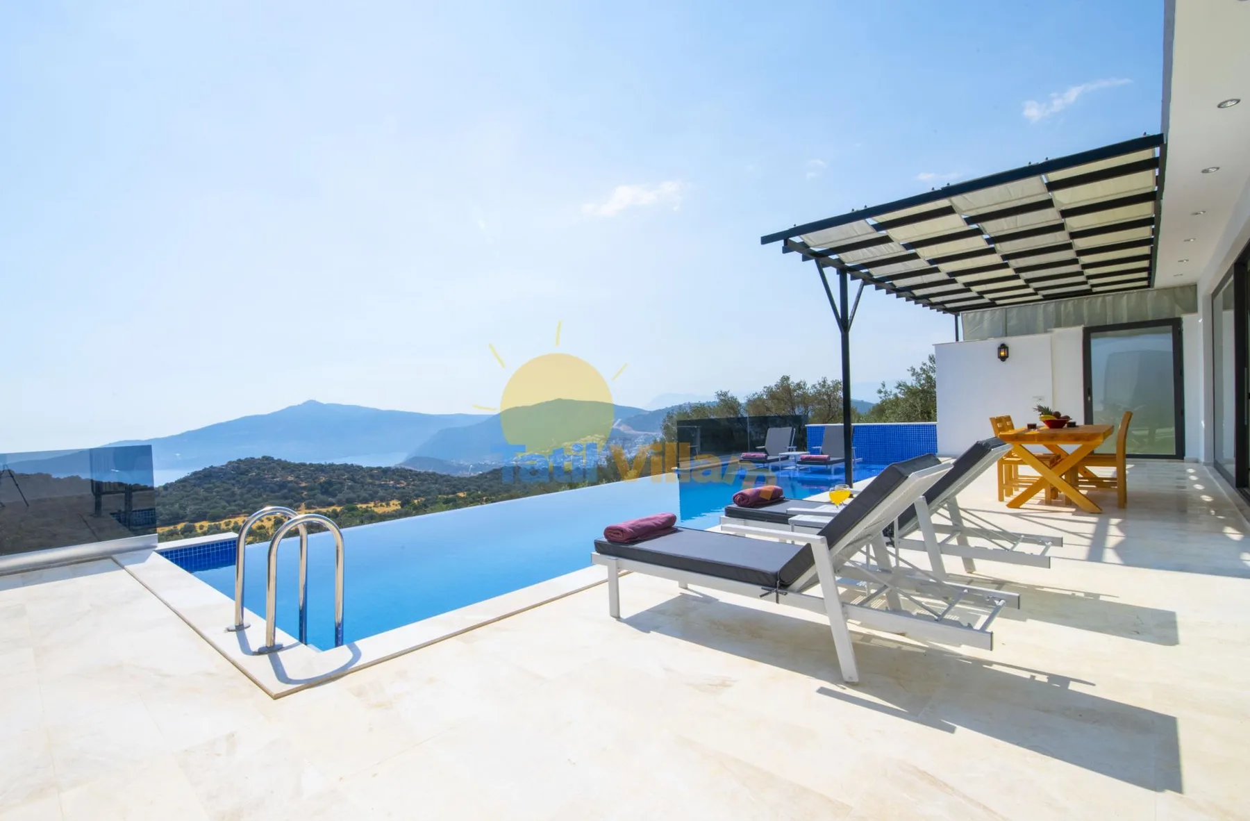 An outdoor poolside terrace with loungers and a mountain view.
