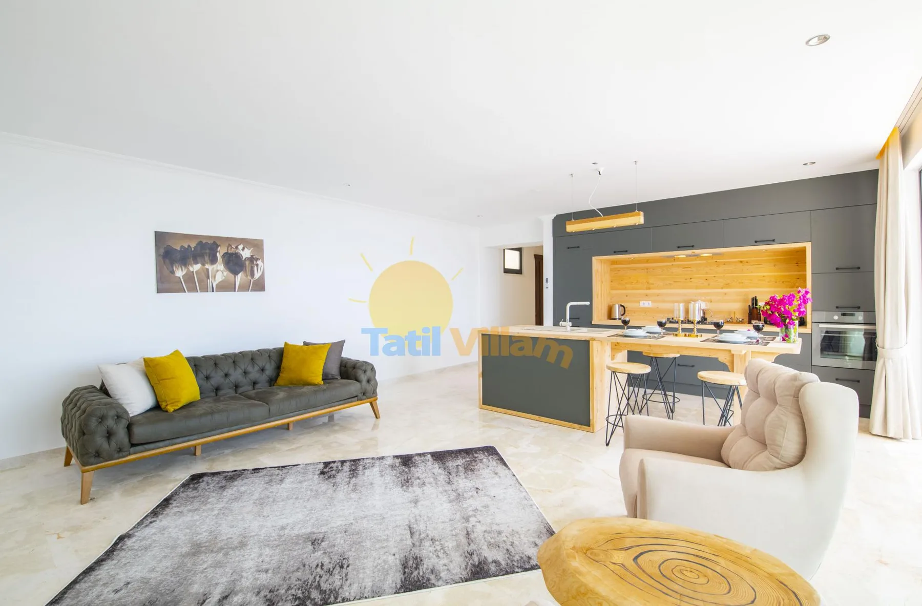 An open-plan living room and kitchen with a gray sofa and island.