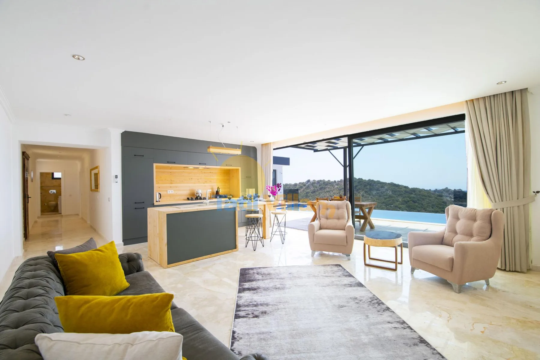 A bright living room opens onto a terrace, with a dining counter and seating.