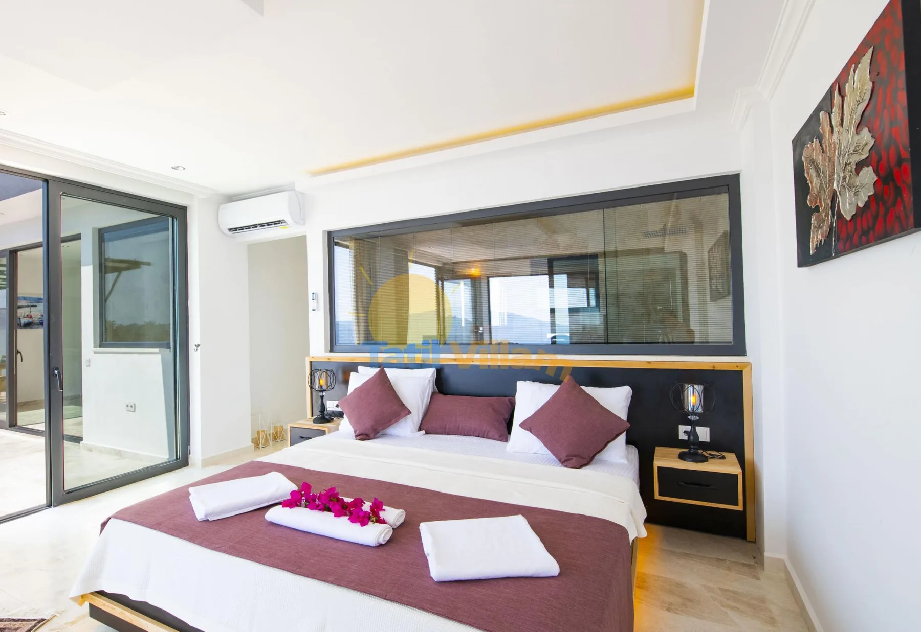 A bedroom with a large bed, folded towels, and glass doors opening to a balcony.