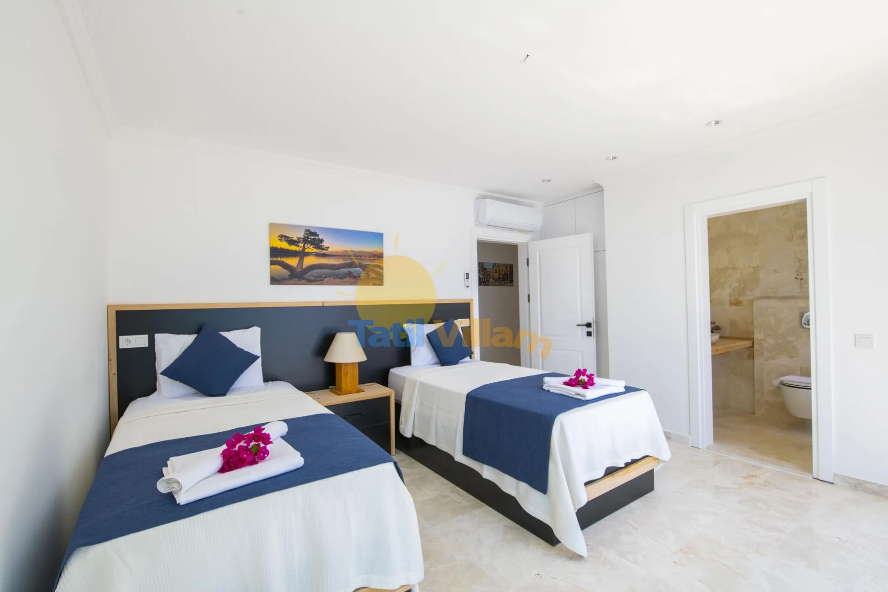A bright bedroom with two beds dressed in white and navy bedding.