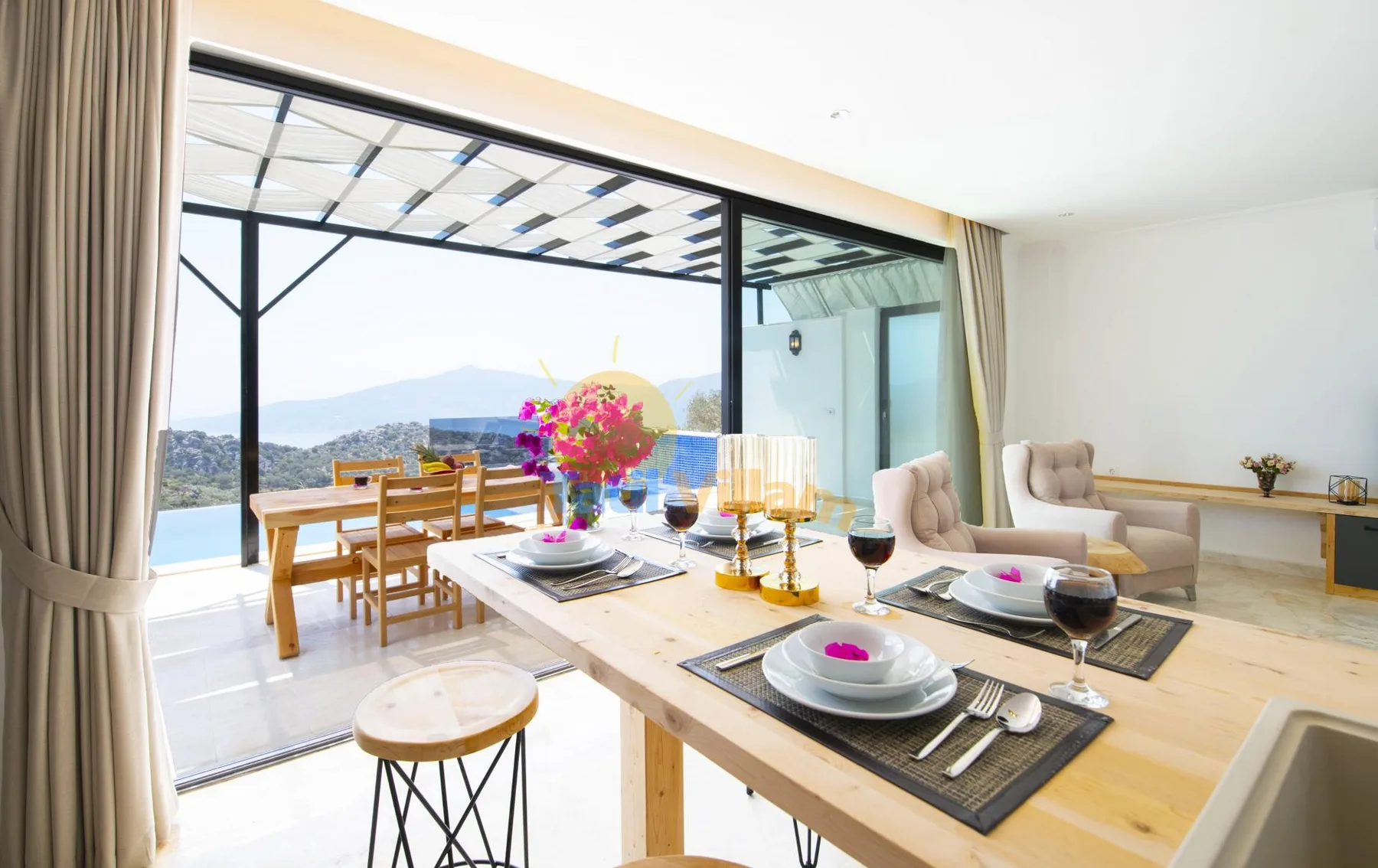 A dining area opens onto a terrace, with a table and seating beside wide glass doors.
