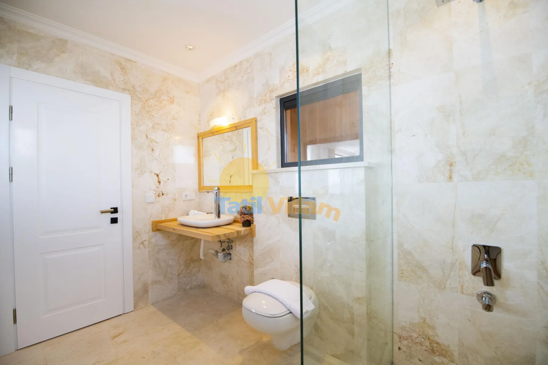 A bathroom with a wall-mounted sink, toilet, and glass shower.
