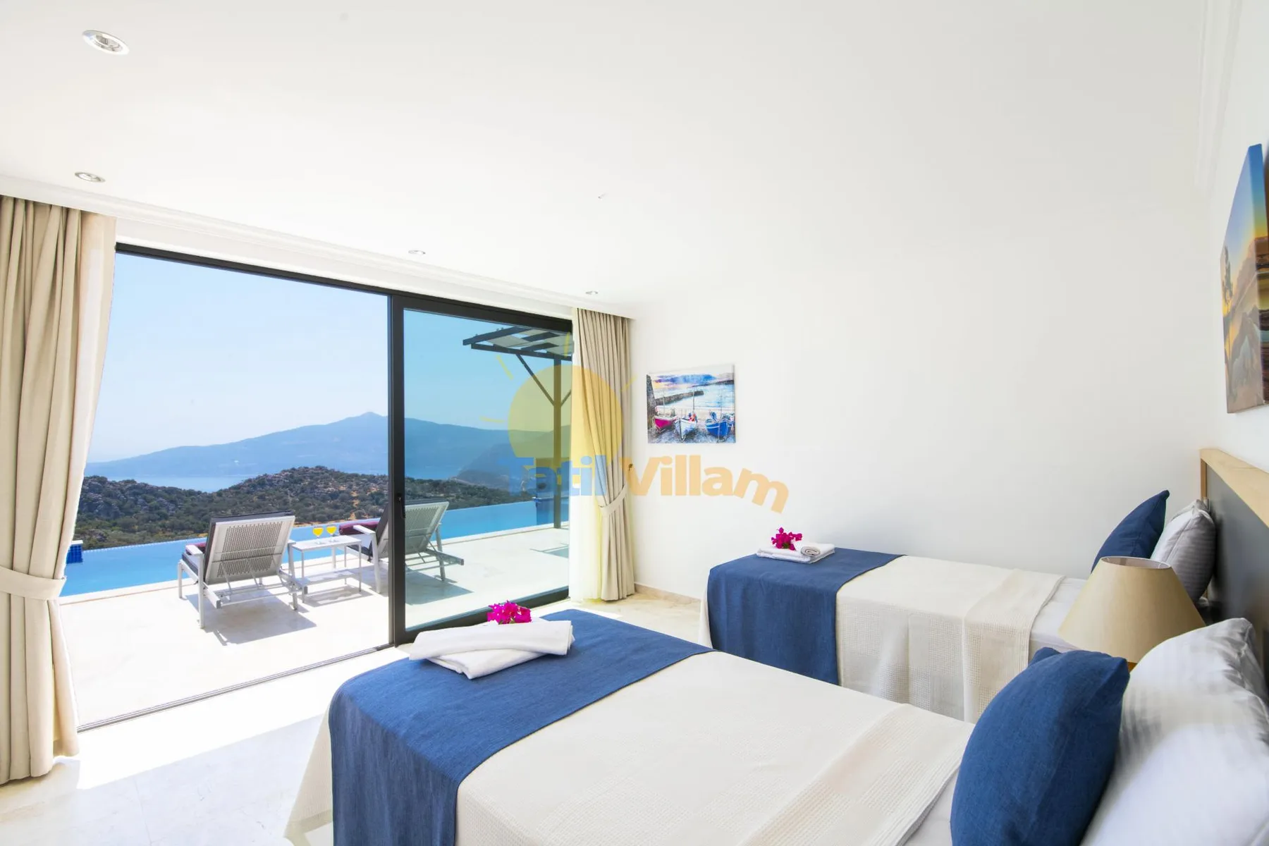 A bright bedroom opens onto a balcony with a view of the sea and hills.