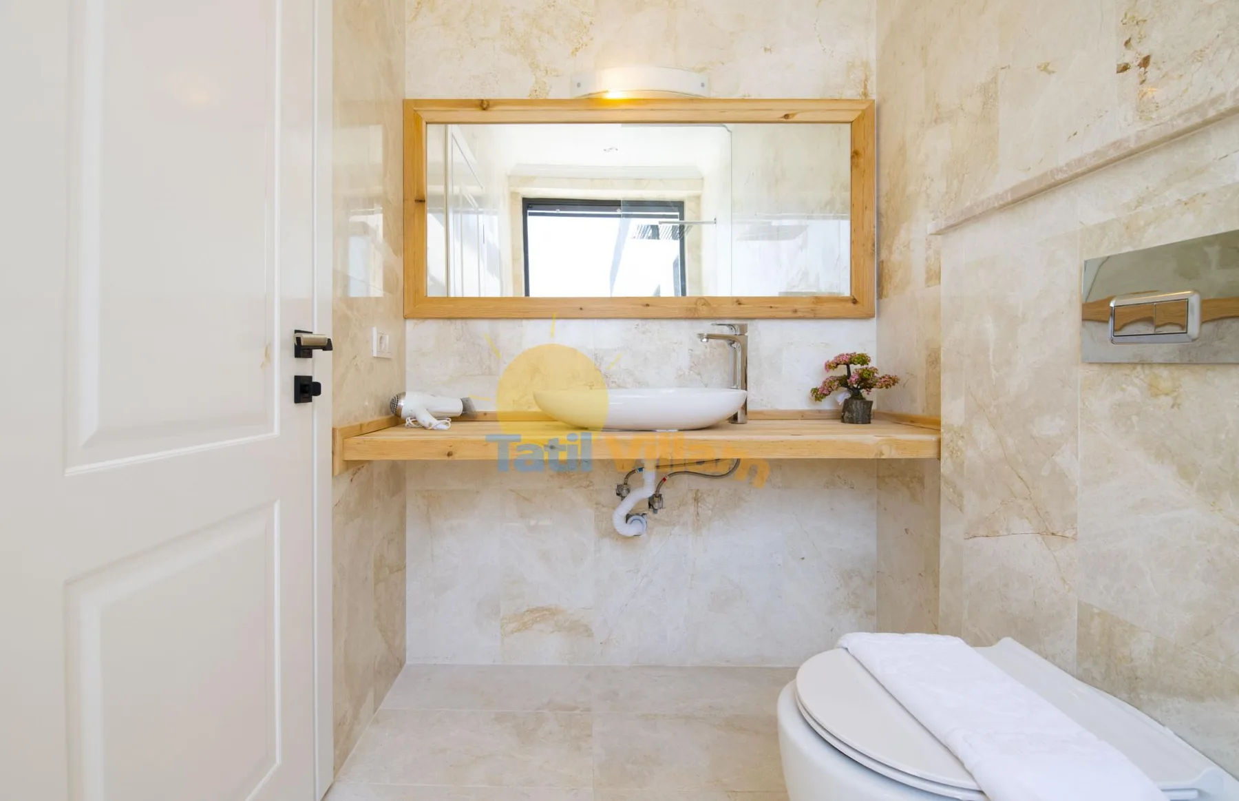A bathroom with a wide mirror above a sink and a toilet in the foreground.