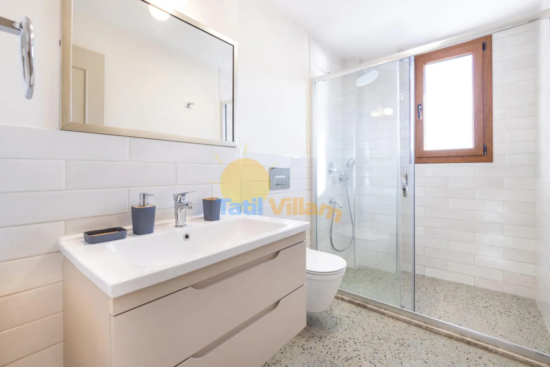 Un baño luminoso con lavabo, espejo, inodoro y ducha de cristal.