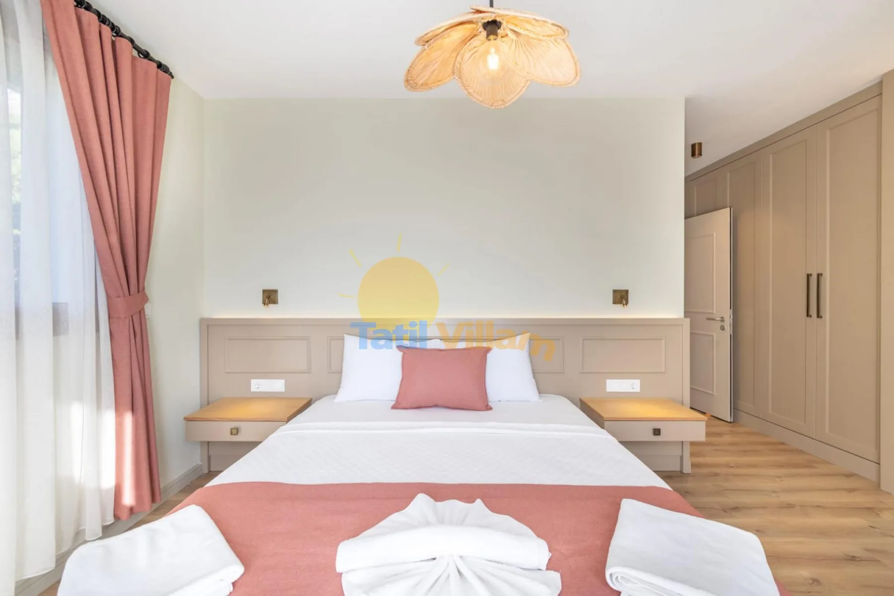 Un dormitorio luminoso con una cama ordenada y cortinas rosas junto a la ventana.