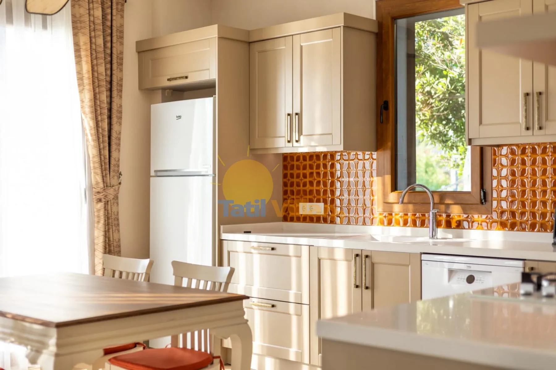 Una cocina luminosa con gabinetes color crema, una encimera y una mesa de comedor.