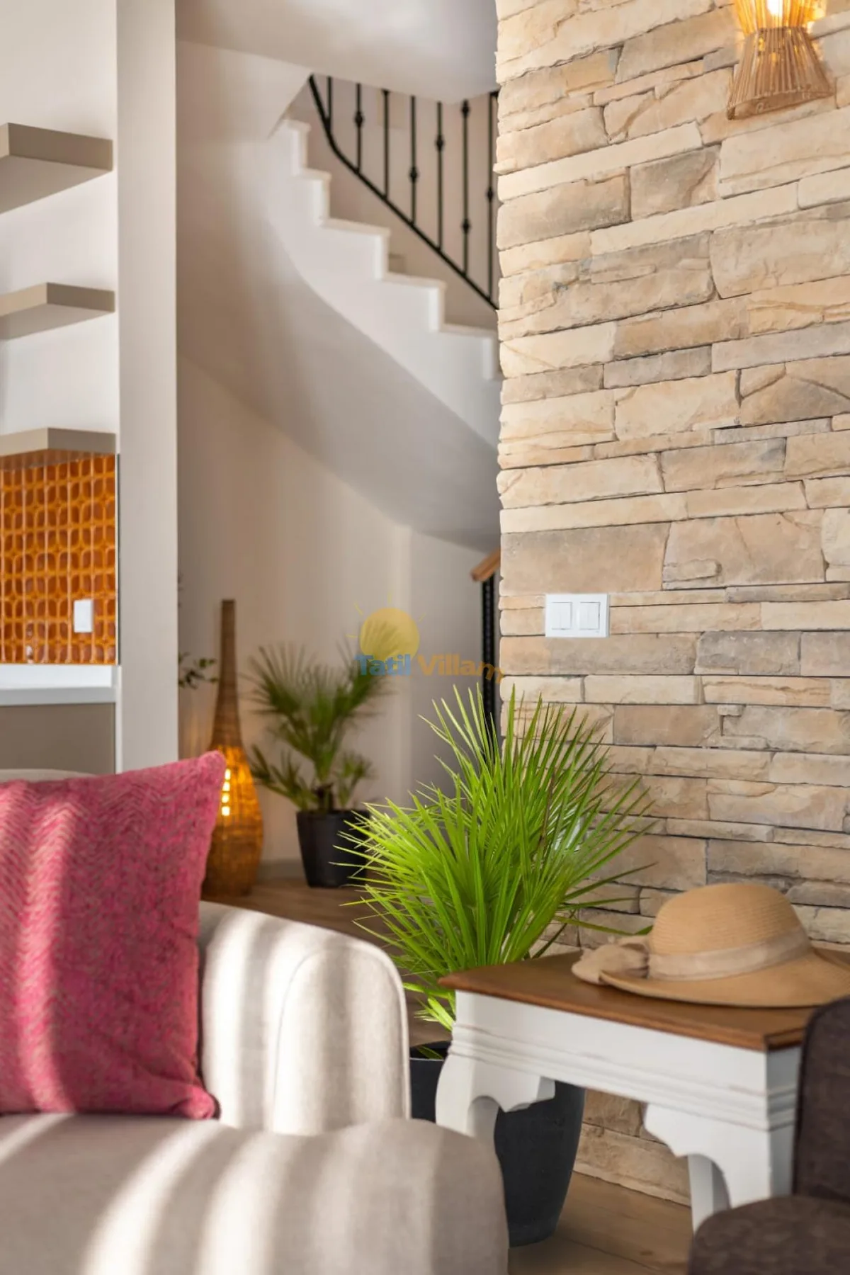Una sala de estar con asientos acolchados, una planta en maceta y una pared decorativa de piedra.