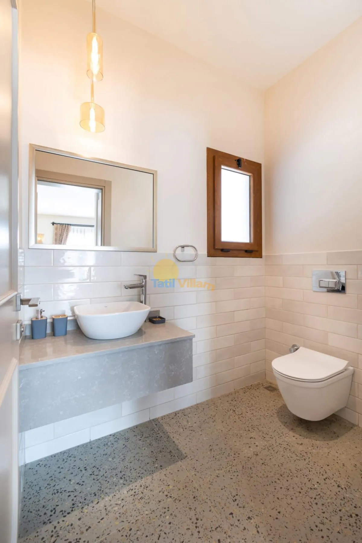 Un baño luminoso con lavabo suspendido, espejo de pared e inodoro suspendido.