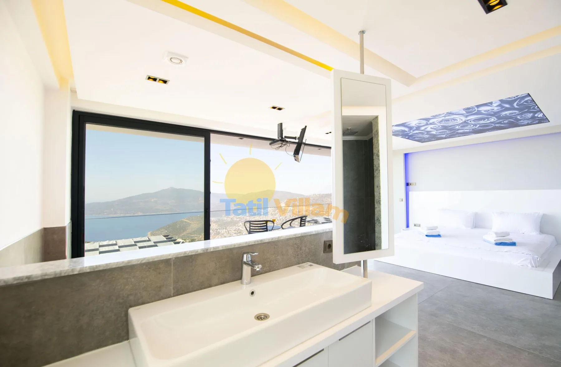 A bright bathroom with a wide sink and a view of the sea through a large window.