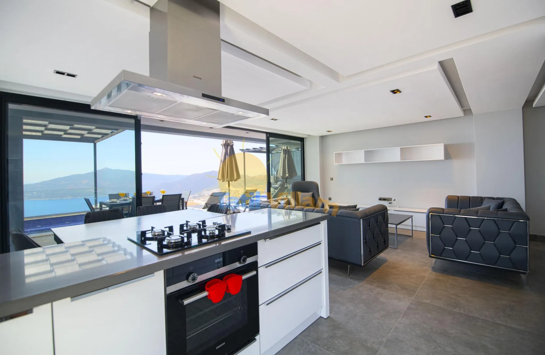 An open-plan kitchen and living area with large windows overlooking the sea.