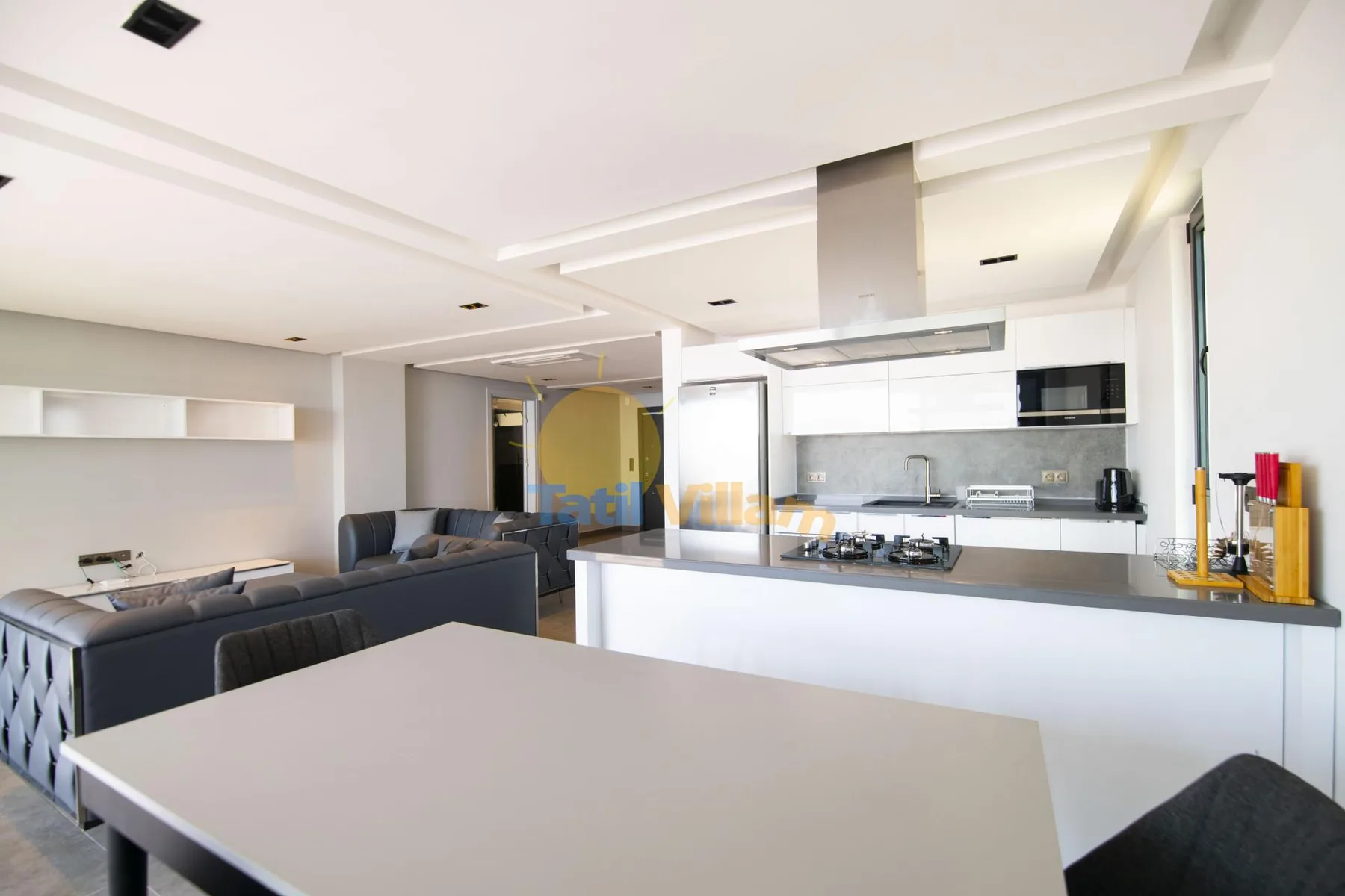 An open-plan kitchen and living area with a dining table in the foreground.