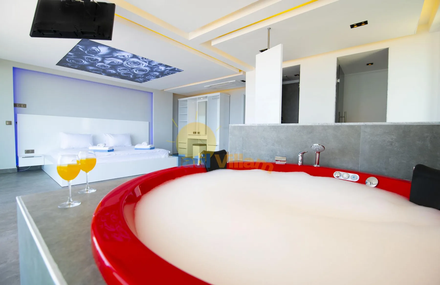 A bedroom with a large round bed, a raised platform, and two yellow stools.