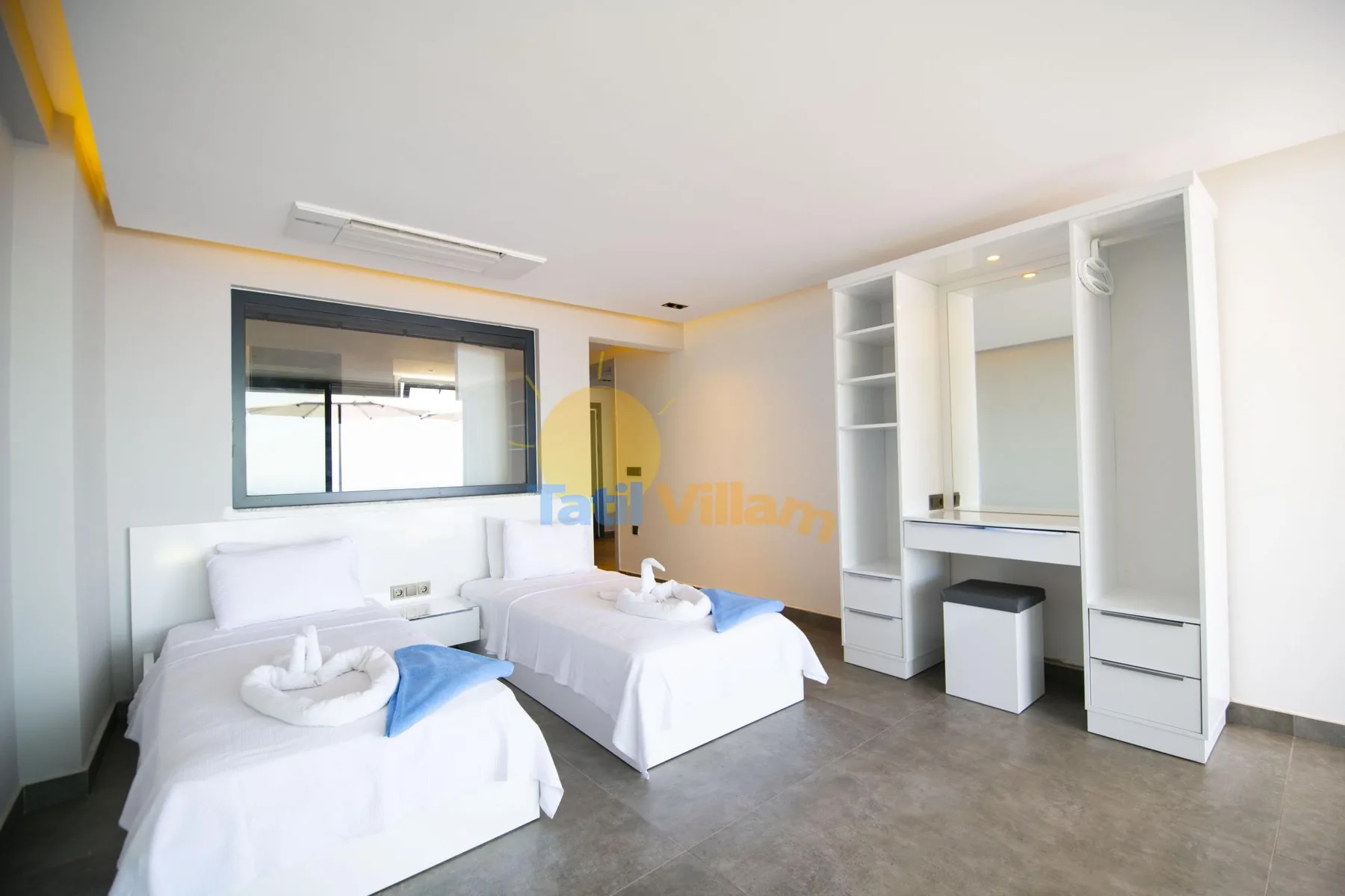 A bright bedroom with two beds and built-in storage along the wall.
