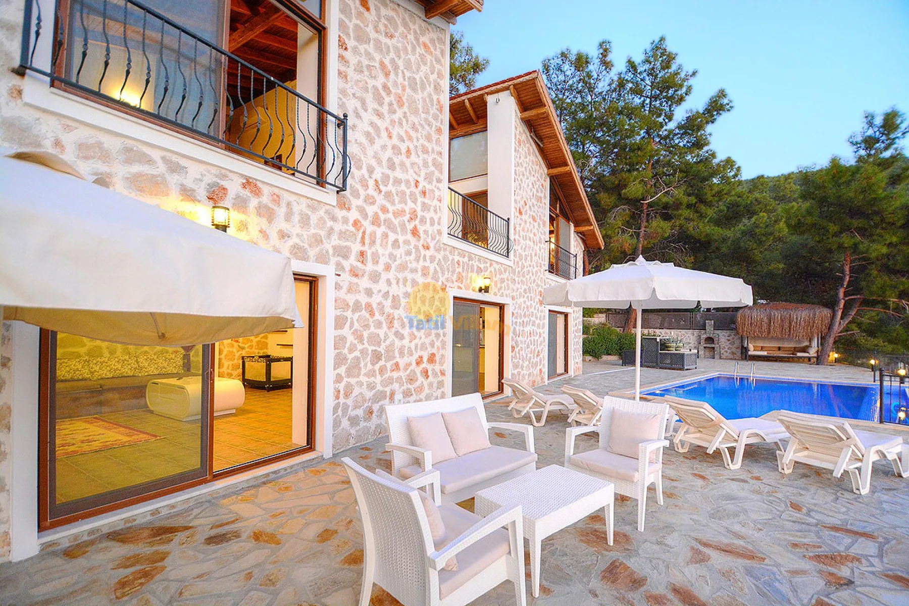 Un edificio revestido de piedra da a un patio con asientos y una piscina.