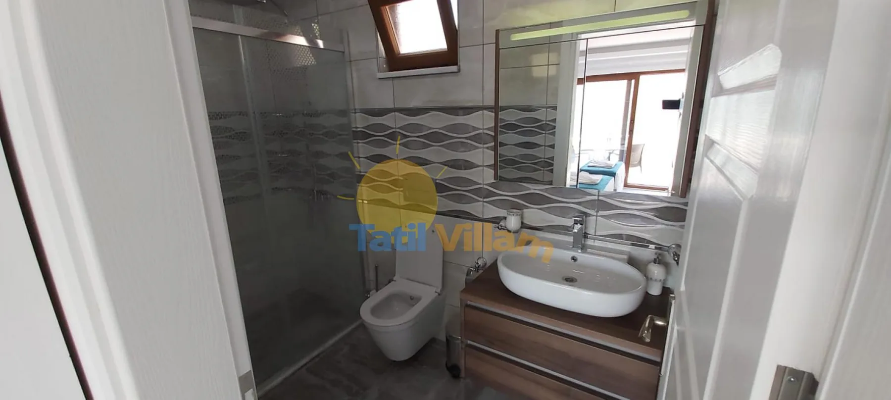 A tiled bathroom with a sink, toilet, and glass shower.