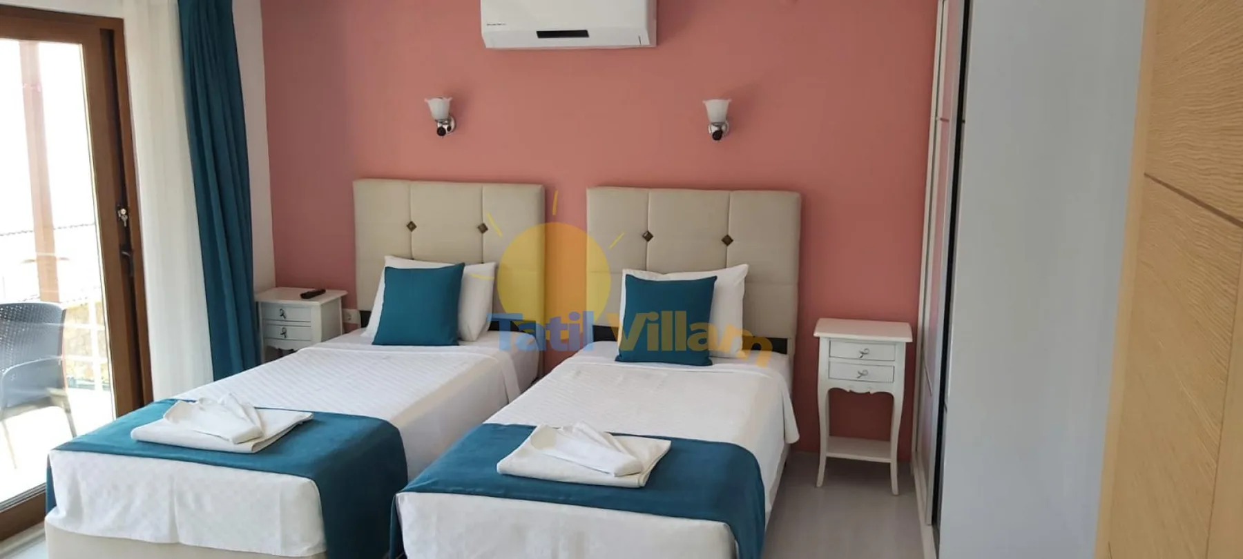 A twin bedroom with two beds against a pink wall.