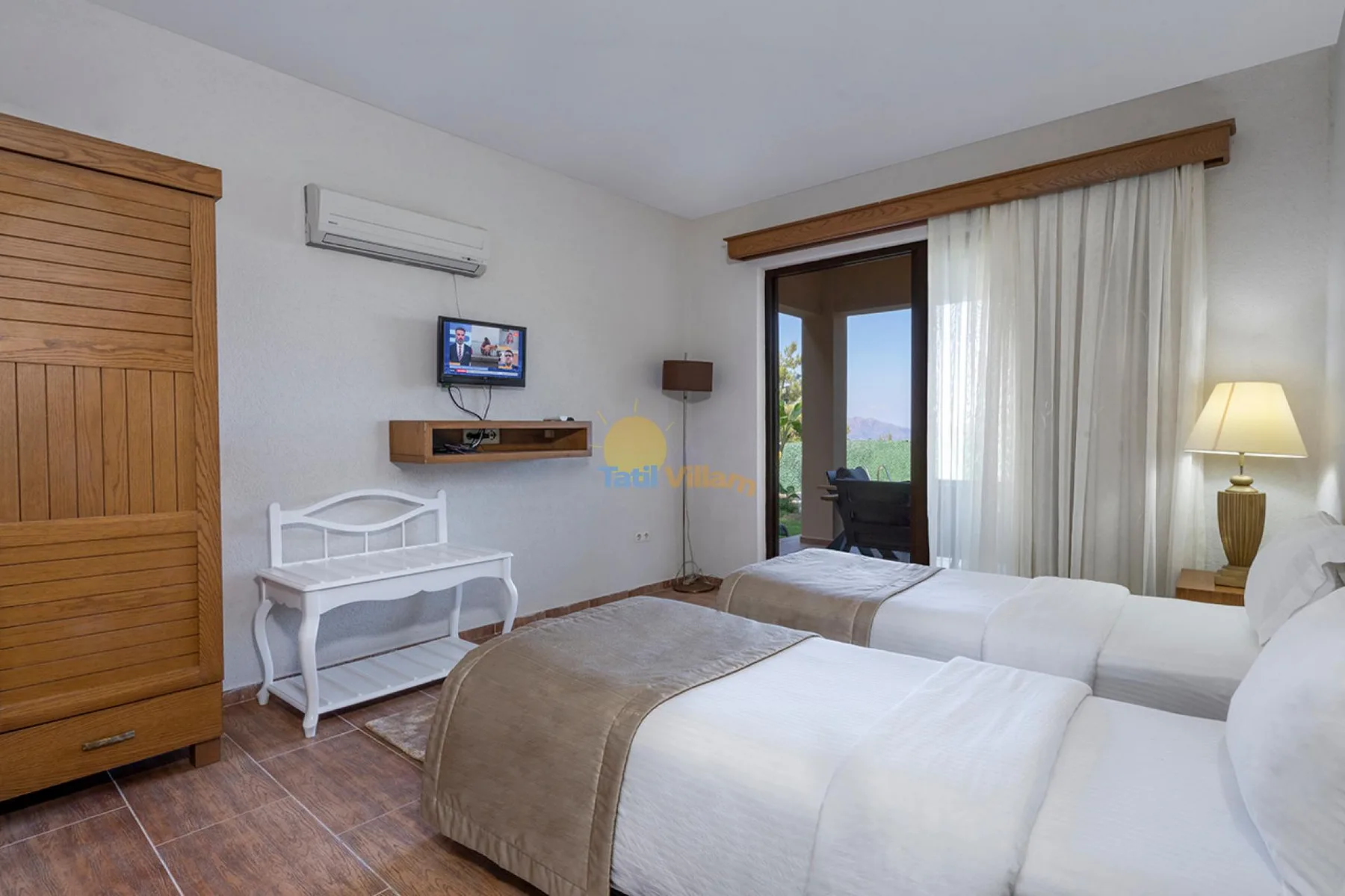 Un dormitorio con dos camas, una mesa pequeña y una puerta de vidrio con cortinas.