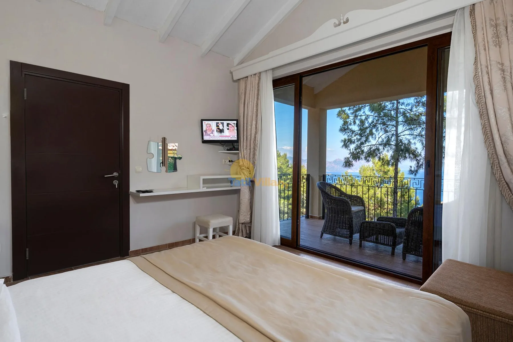Un dormitorio da a un balcón con asientos al aire libre y vistas a los árboles.