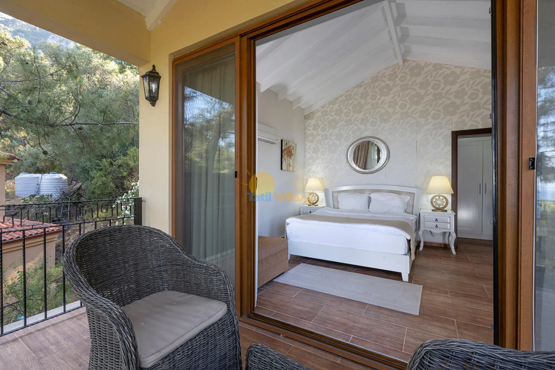 Un dormitorio con una cama blanca y mesitas de noche da a un balcón.