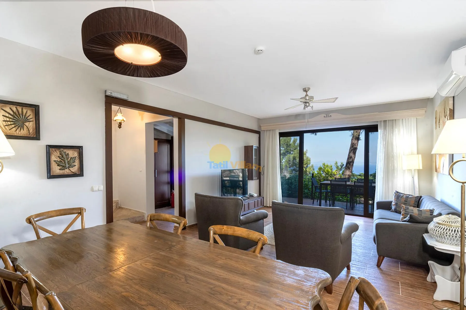 Una sala de estar y comedor con mesa de madera y asientos junto a puertas de cristal.