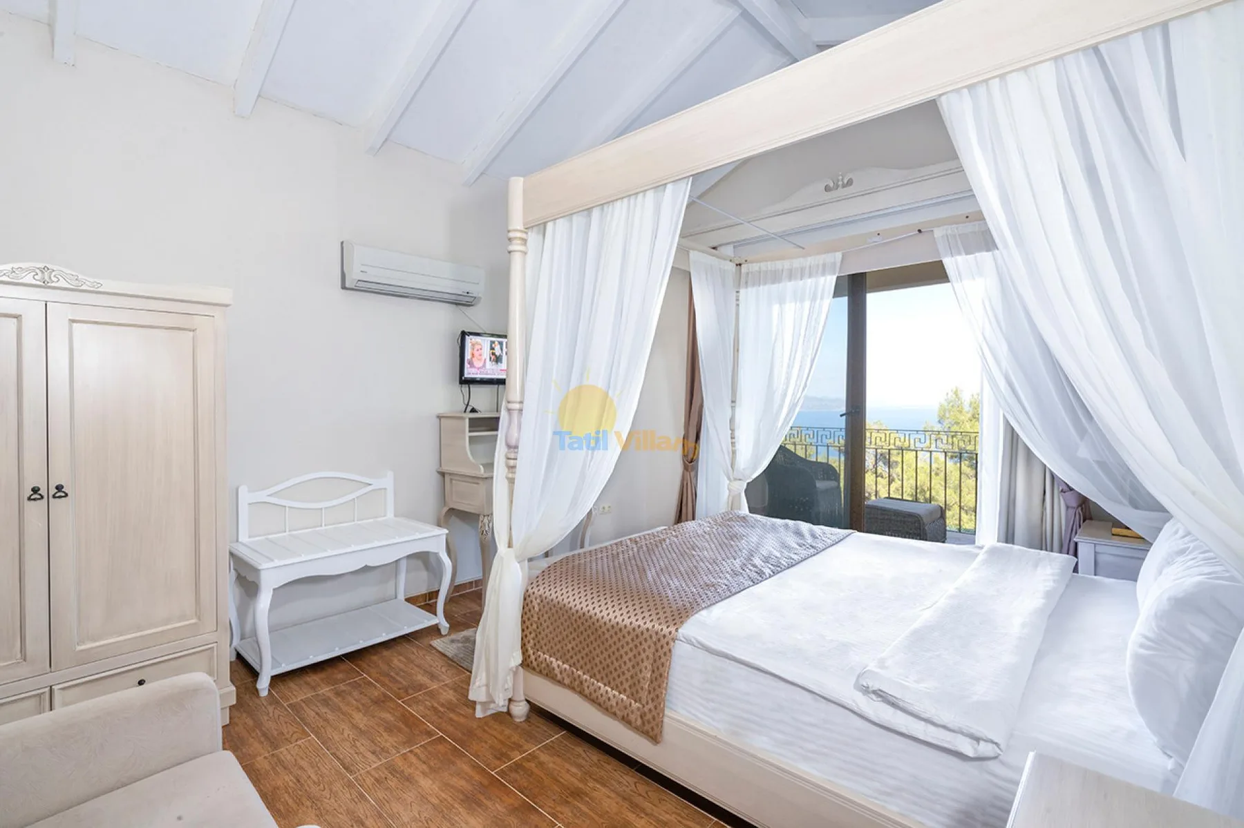 Un dormitorio luminoso con cama con dosel junto a puertas de cristal que dan a un balcón.