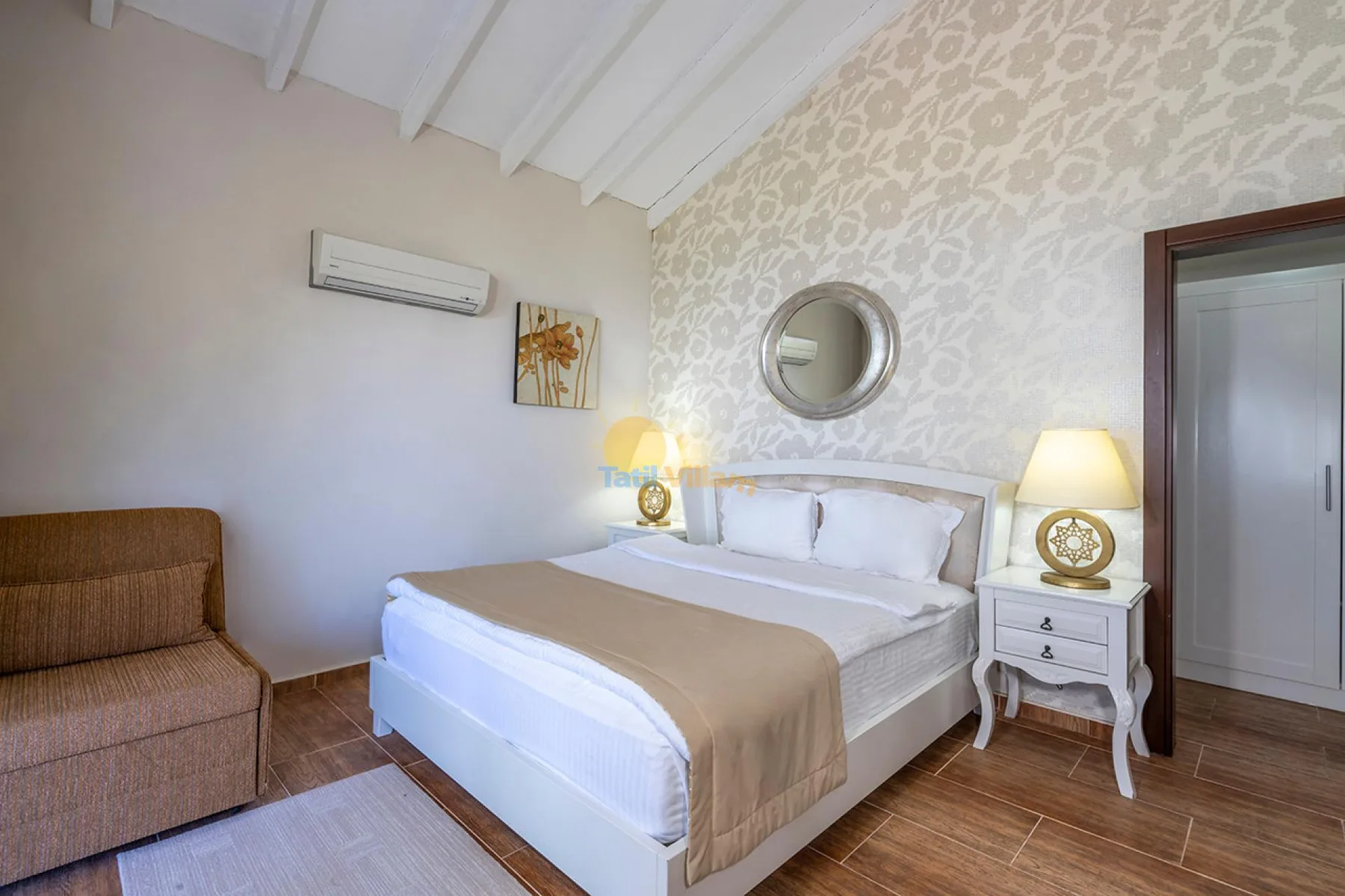 Un dormitorio con una cama, mesitas de noche y una silla tapizada.