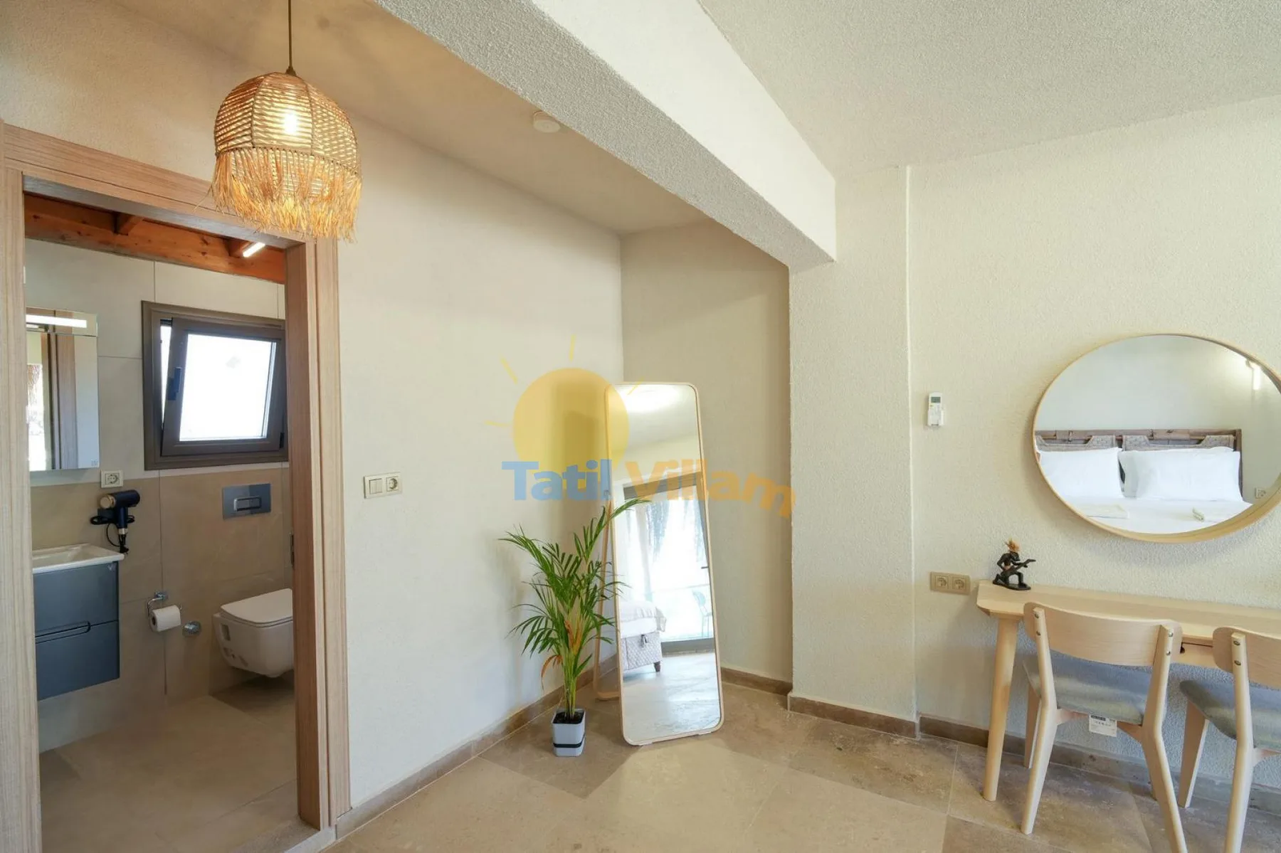 Una habitación luminosa con una puerta al baño, una planta y una pequeña zona de comedor.
