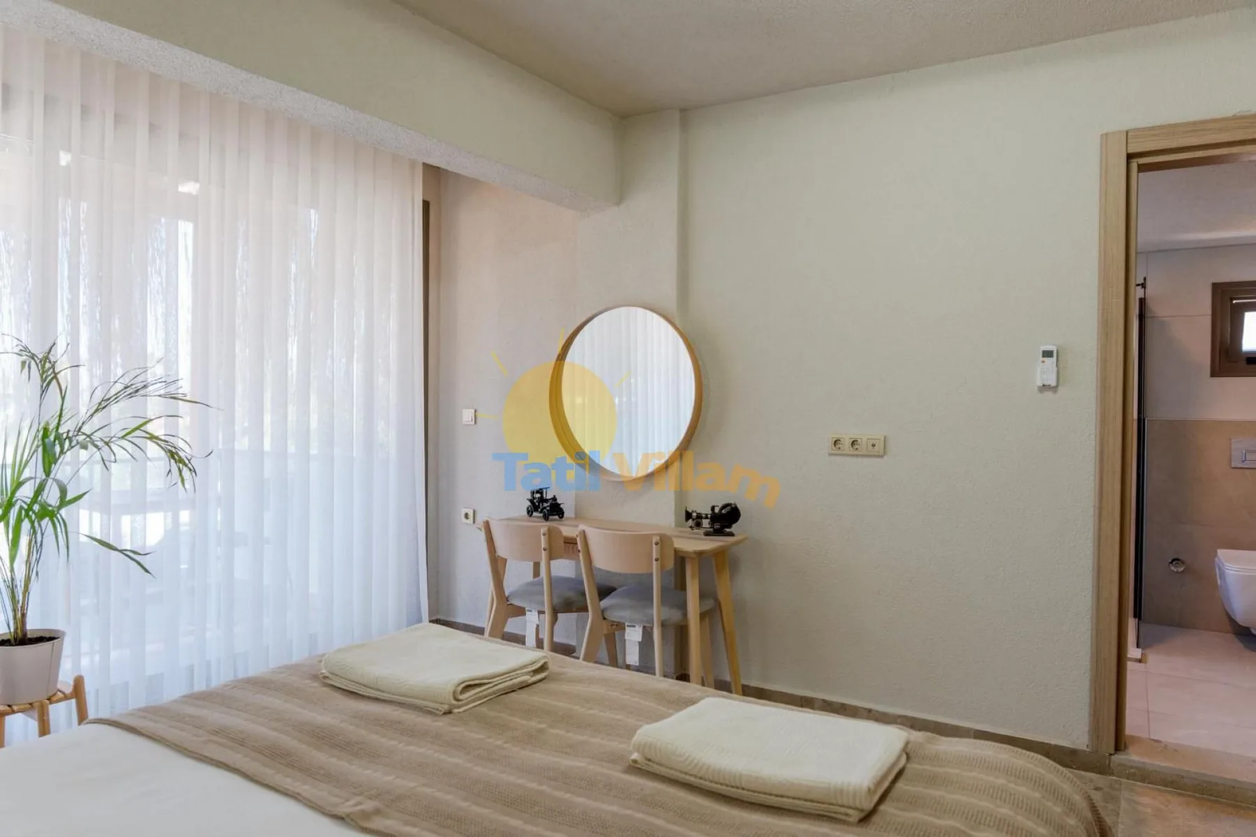 Un dormitorio con una cama, un escritorio pequeño y un espejo redondo.