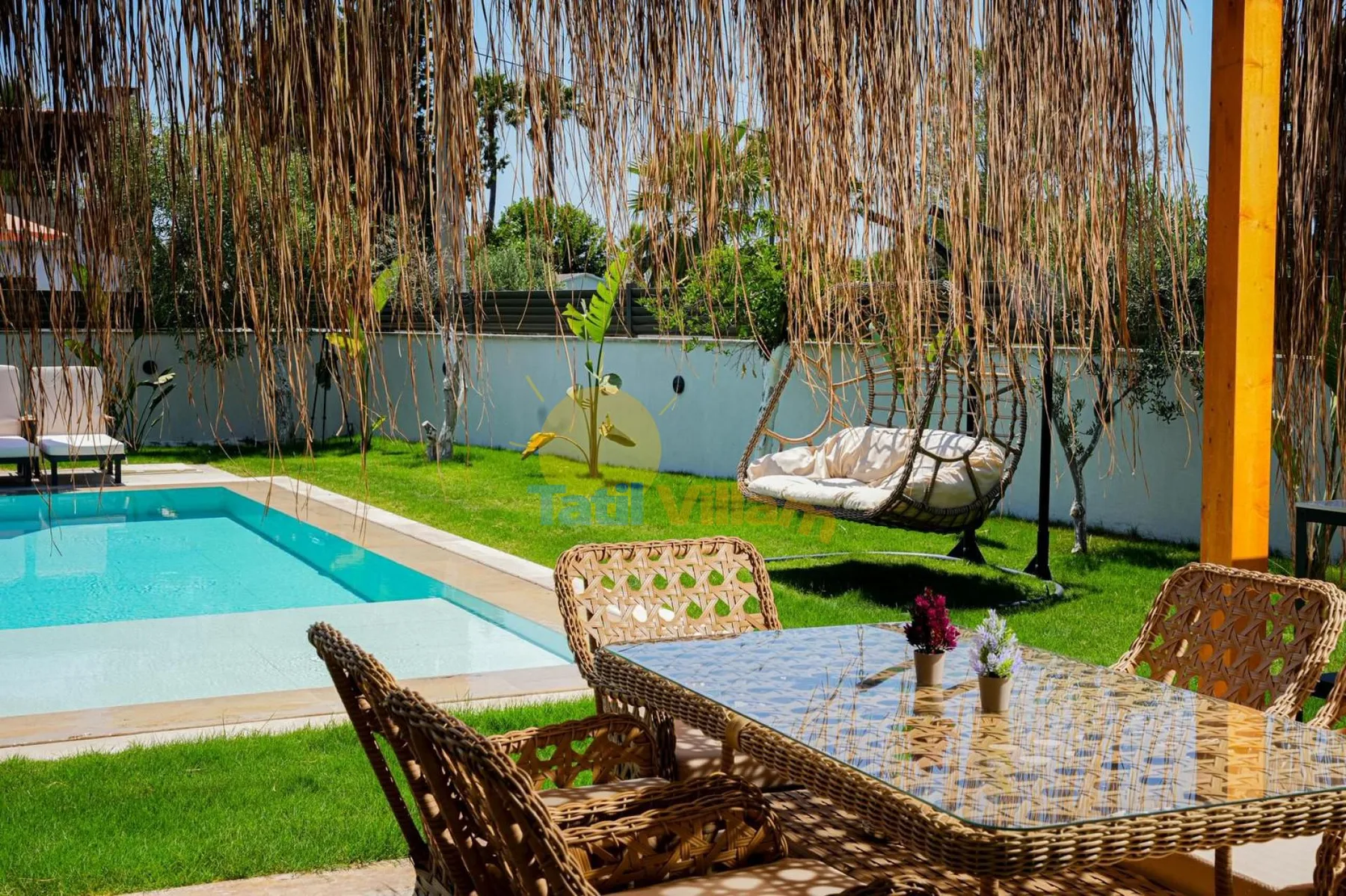 Una piscina exterior y asientos en el patio junto a un jardín con césped.