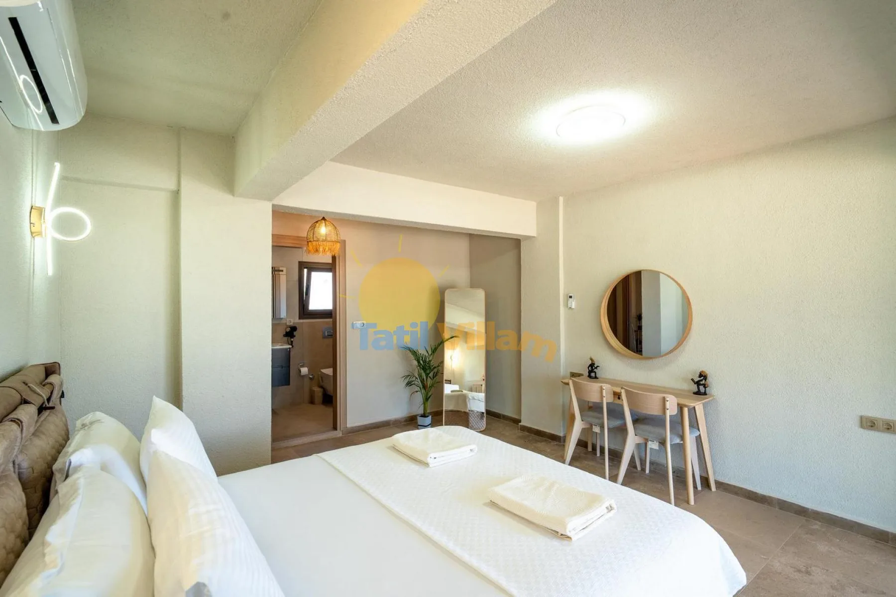 Un dormitorio con una cama, una mesa pequeña y un baño contiguo.