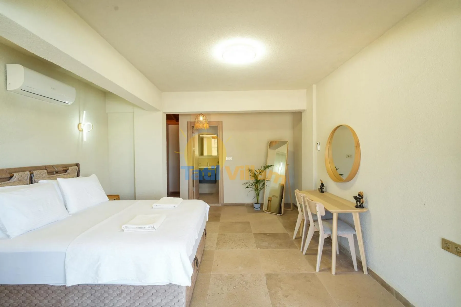Un dormitorio luminoso con una cama, una mesa pequeña y un espejo de pared.