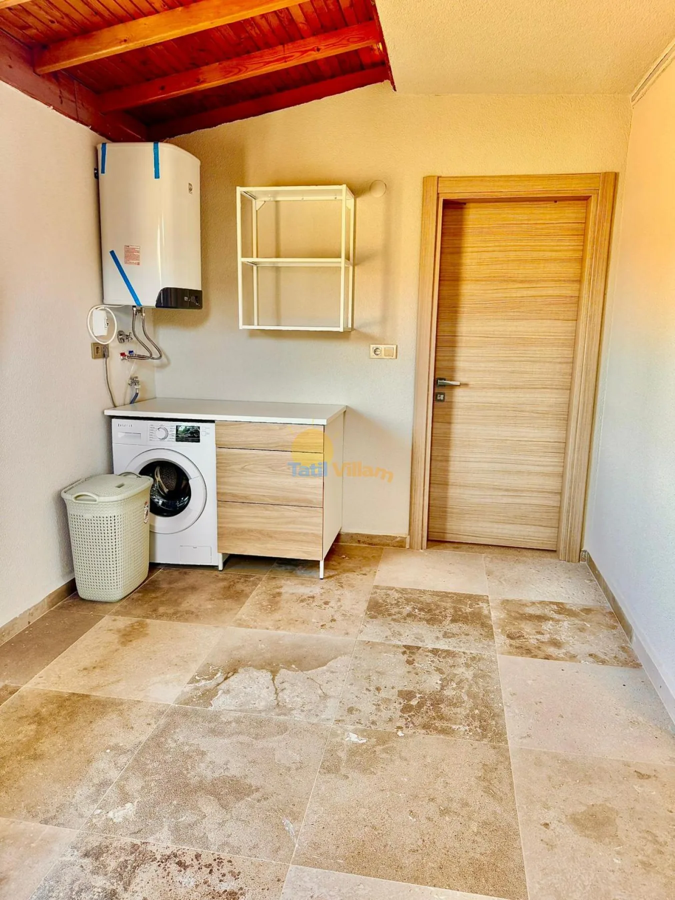 Zona de lavandería con una lavadora, equipo de servicio y una puerta de madera.