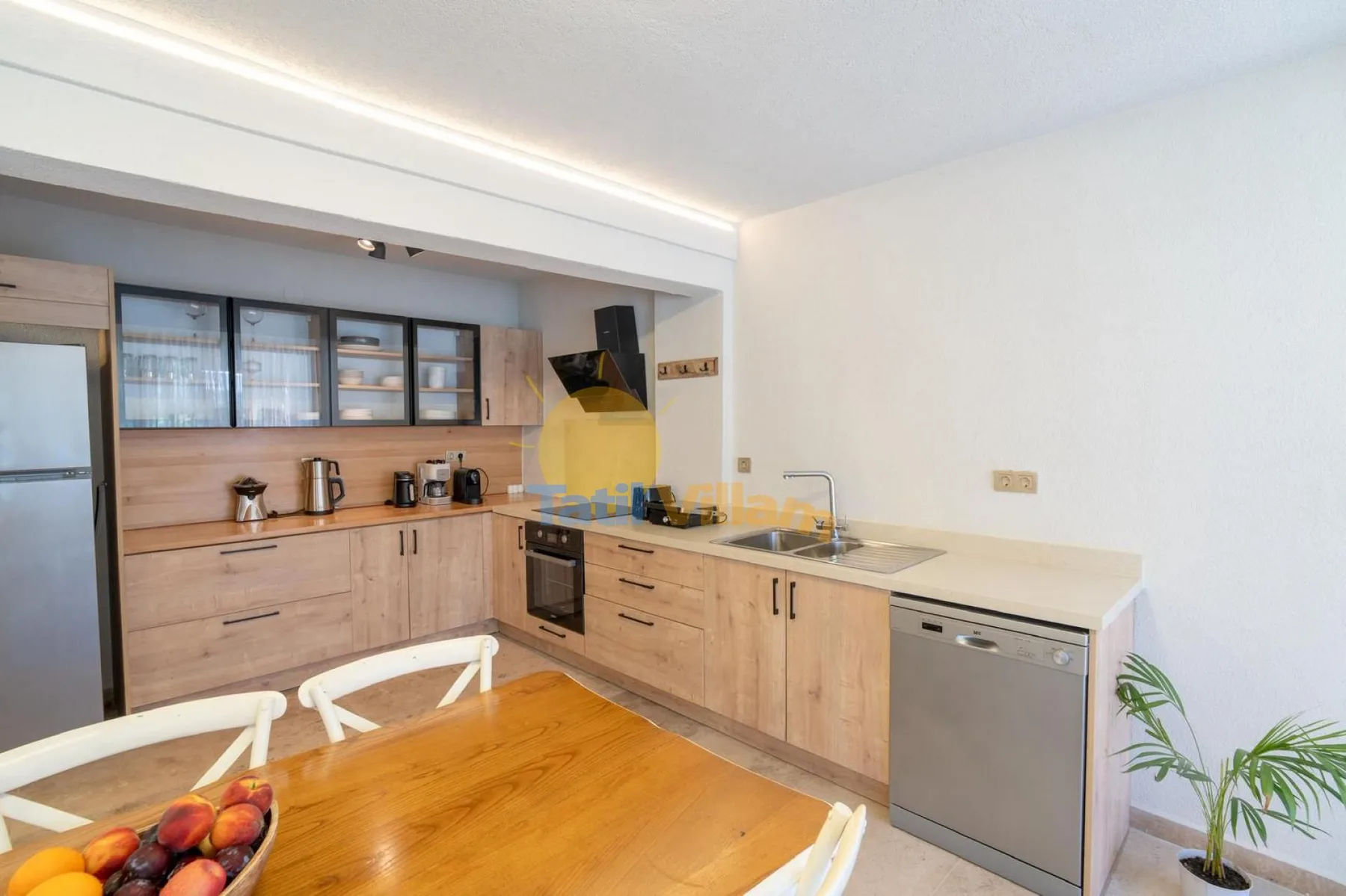 Una cocina luminosa con gabinetes de madera, electrodomésticos de encimera y una mesa de comedor.