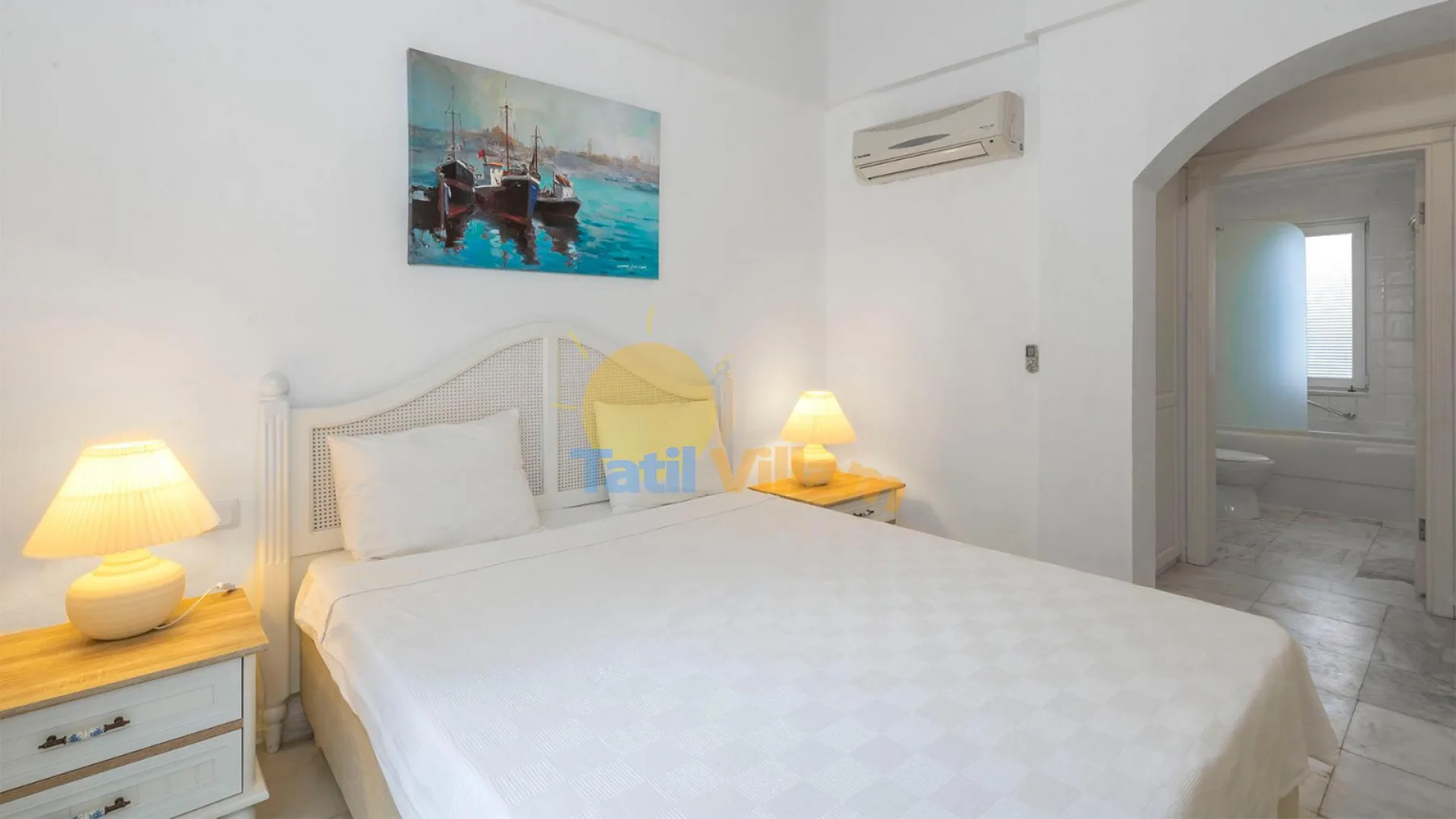 Un dormitorio luminoso con una cama doble, mesas de noche y un cuadro sobre el cabecero.