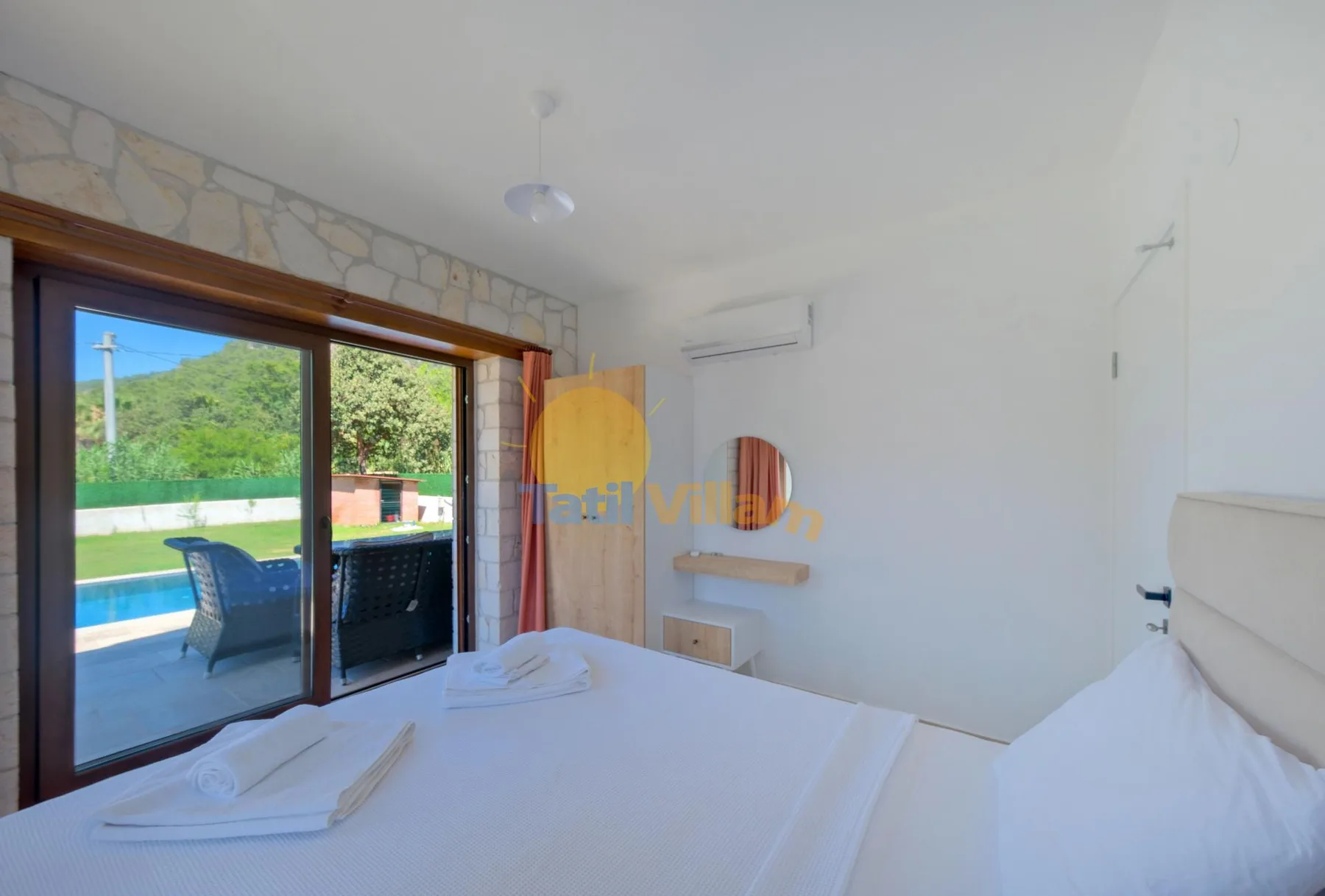 Un dormitorio luminoso con una cama junto a grandes puertas corredizas de vidrio con vistas a una piscina.
