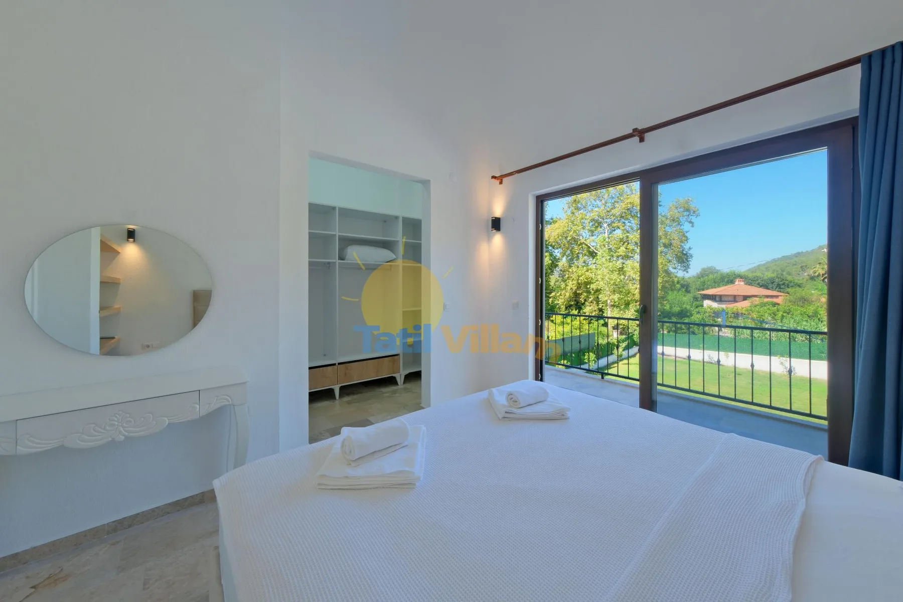 Un dormitorio con una cama bien tendida junto a grandes puertas de vidrio que dan a un balcón.