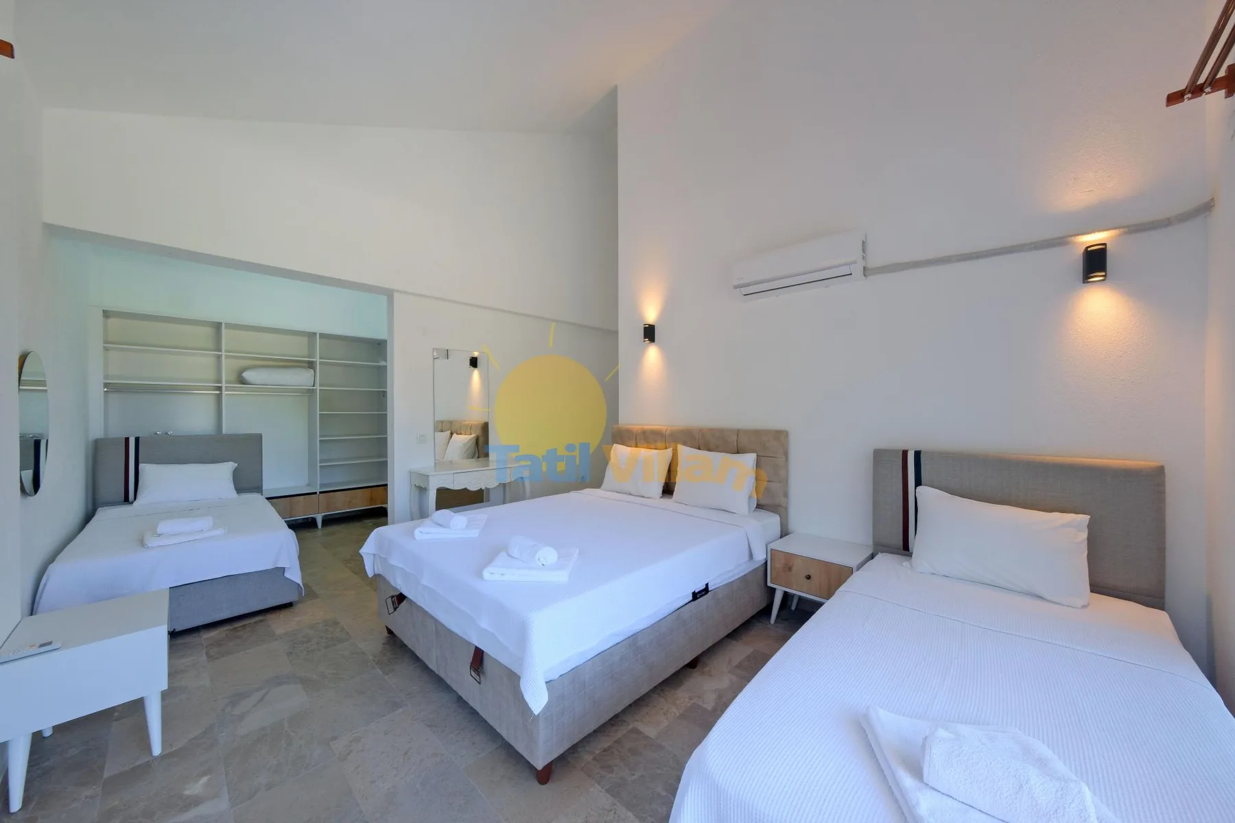 Un dormitorio luminoso con camas y estanterías empotradas junto a la pared.