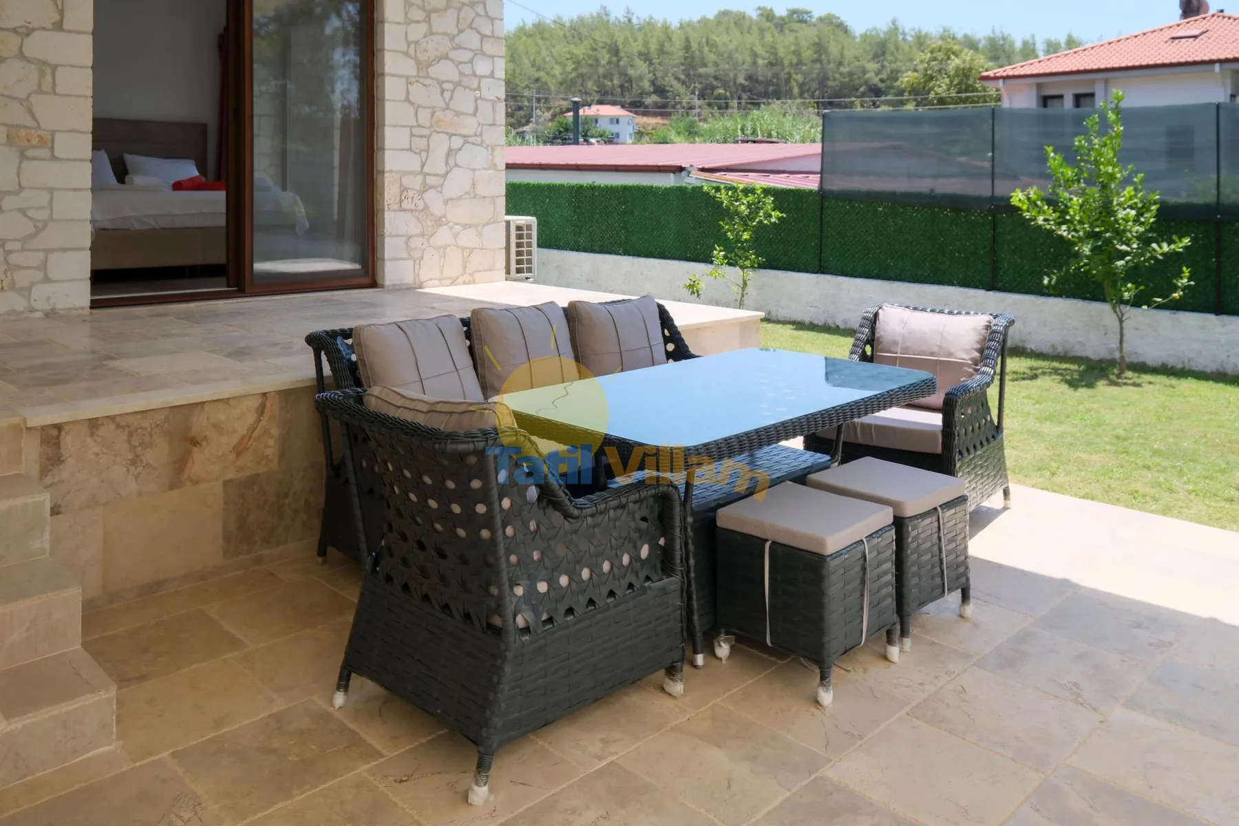 Una zona de comedor en el patio, con mesa y asientos acolchados junto a la casa.