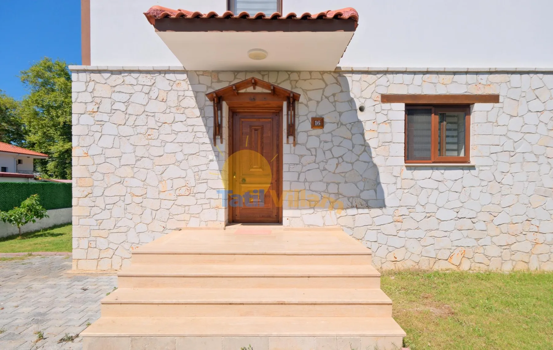 Entrada de edificio revestido de piedra con puerta de madera y escalones amplios.