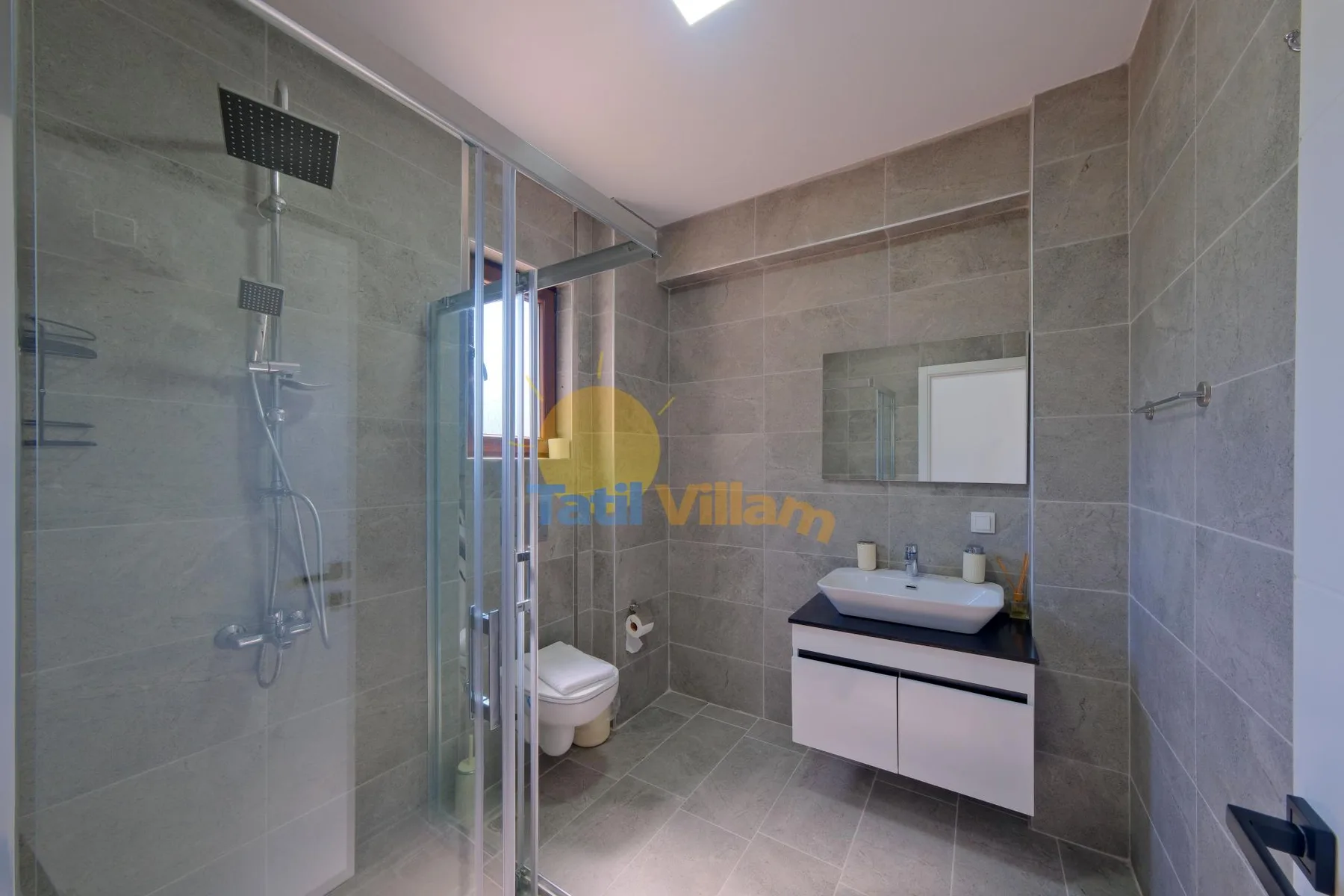 Un baño alicatado con una ducha de vidrio y un lavabo con mueble.